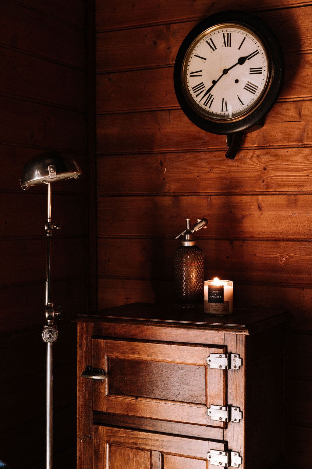 The Inn Beechworth, Luxury Accommodation - Kelllly House. Whiskey Room featuring a wooden cabinet, a lit candle, a vintage siphon bottle, and a wall-mounted clock with Roman numerals. T