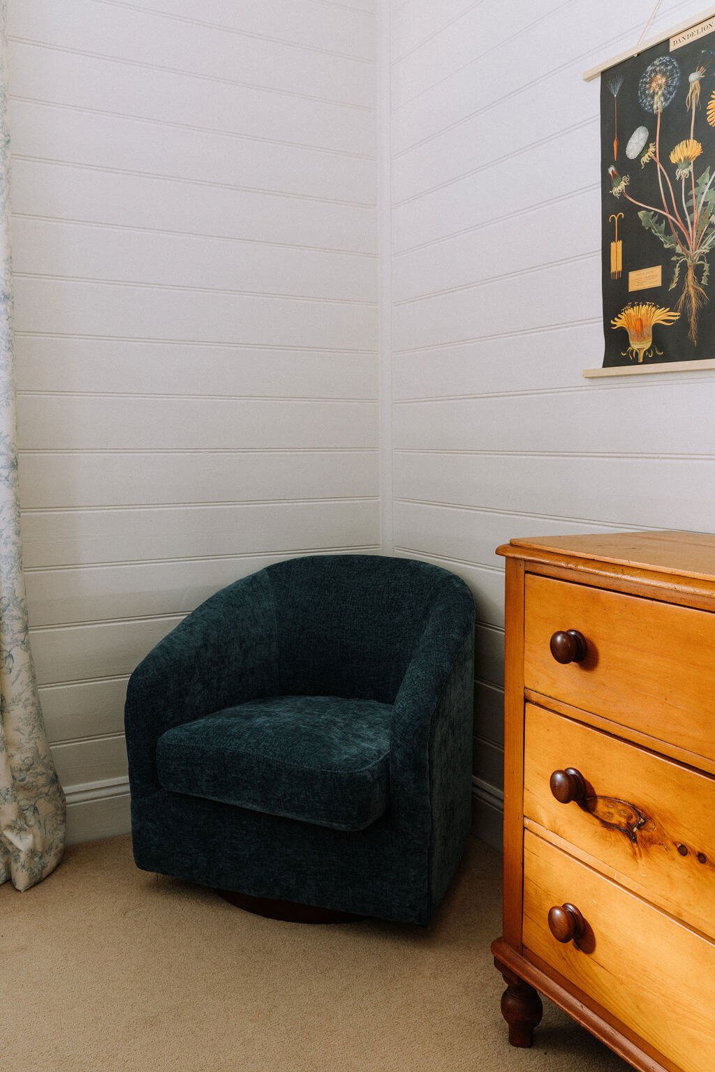The Inn Beechworth, Luxury Accommodation - Kelly House. Corner of a room with a green upholstered chair, a wooden dresser with three drawers, a botanical wall art poster, and light-colored floral curtains.