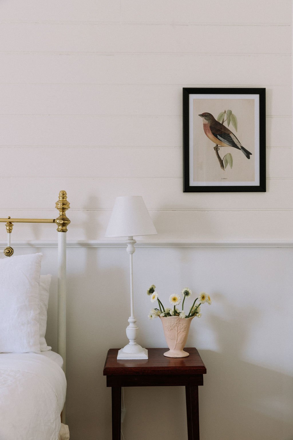 The Inn Beechworth, Luxury Accommodation - Kelly House. A bedroom scene with a white metal bed frame, white linens, a wooden nightstand, and a white table lamp.