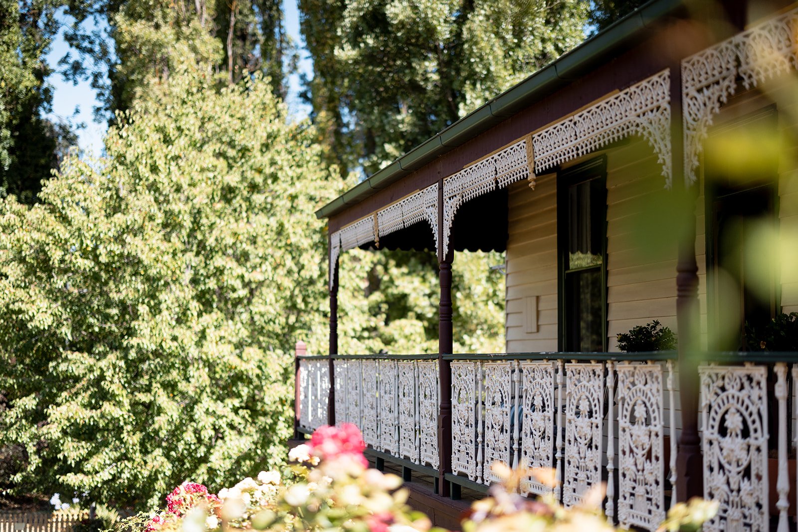 Kelly House whiskey room is a cosy living room with wooden walls and ireplace, featuring a round wooden table with two glasses of whiskey and a bottle, surrounded by upholstered chairs and a sofa.