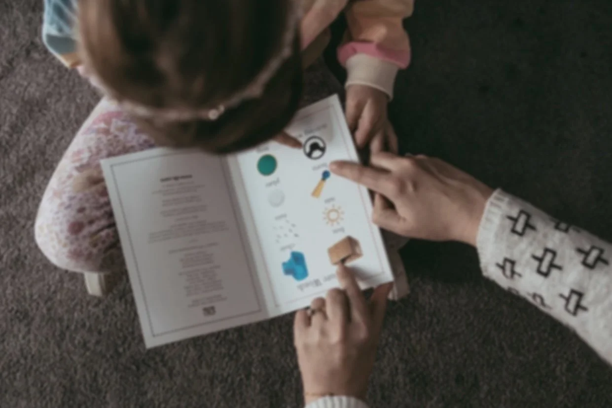 Child reading decodable book with help from adult