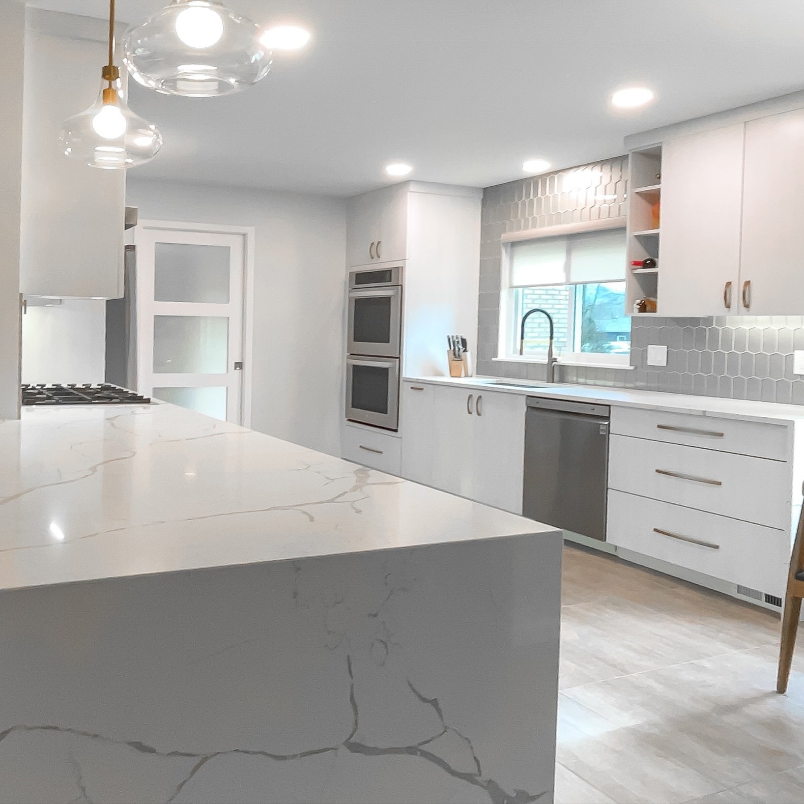 ✨ Modern Elegance ✨ Loving the sleek gray cabinetry, white marble countertops, and herringbone backsplash in this kitchen remodel. The warm-toned wood flooring adds a cozy touch.