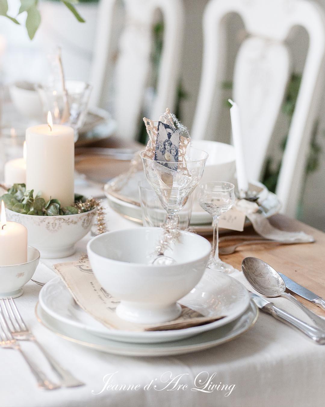 Juledekoration på spisebord med stearinlys, porcelænsservice og julepynt i glas.
