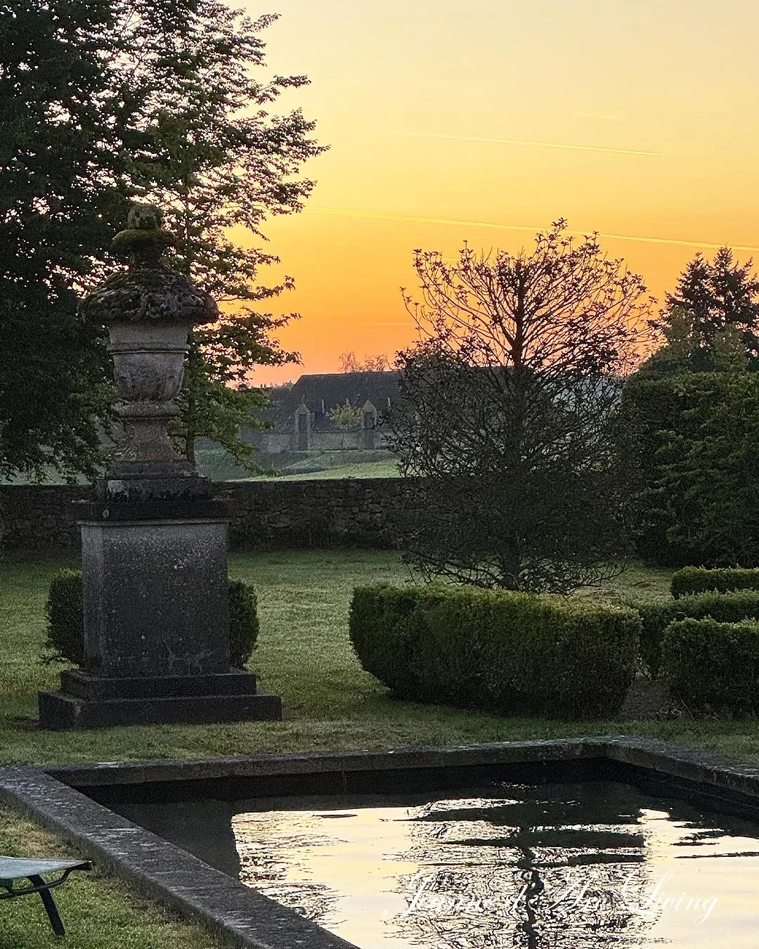 Have med statue og bassin i solnedgang