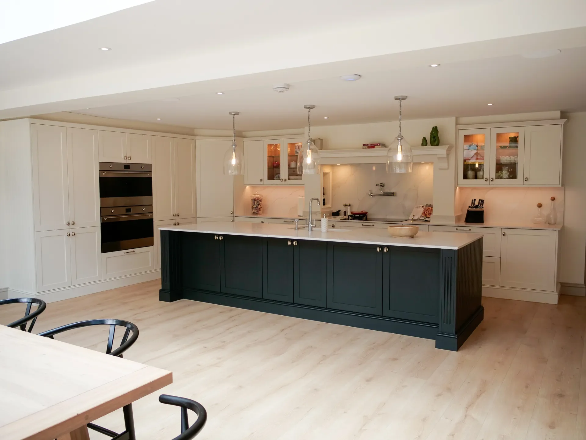 Modern kitchen with white cabinets, dark island, and pendant lights.