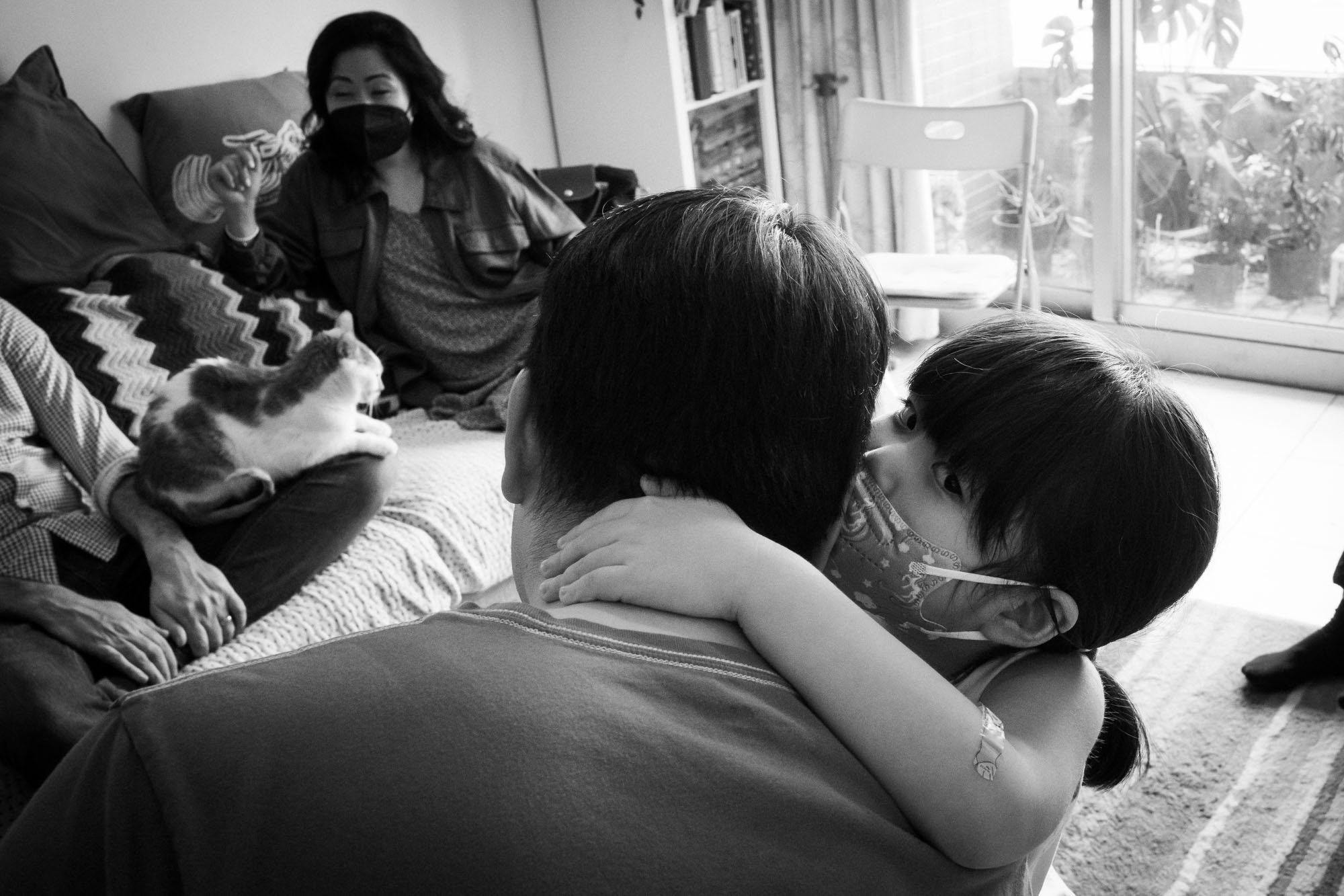 A little girl whispers in her father's ear in an apartment in Taipei.
