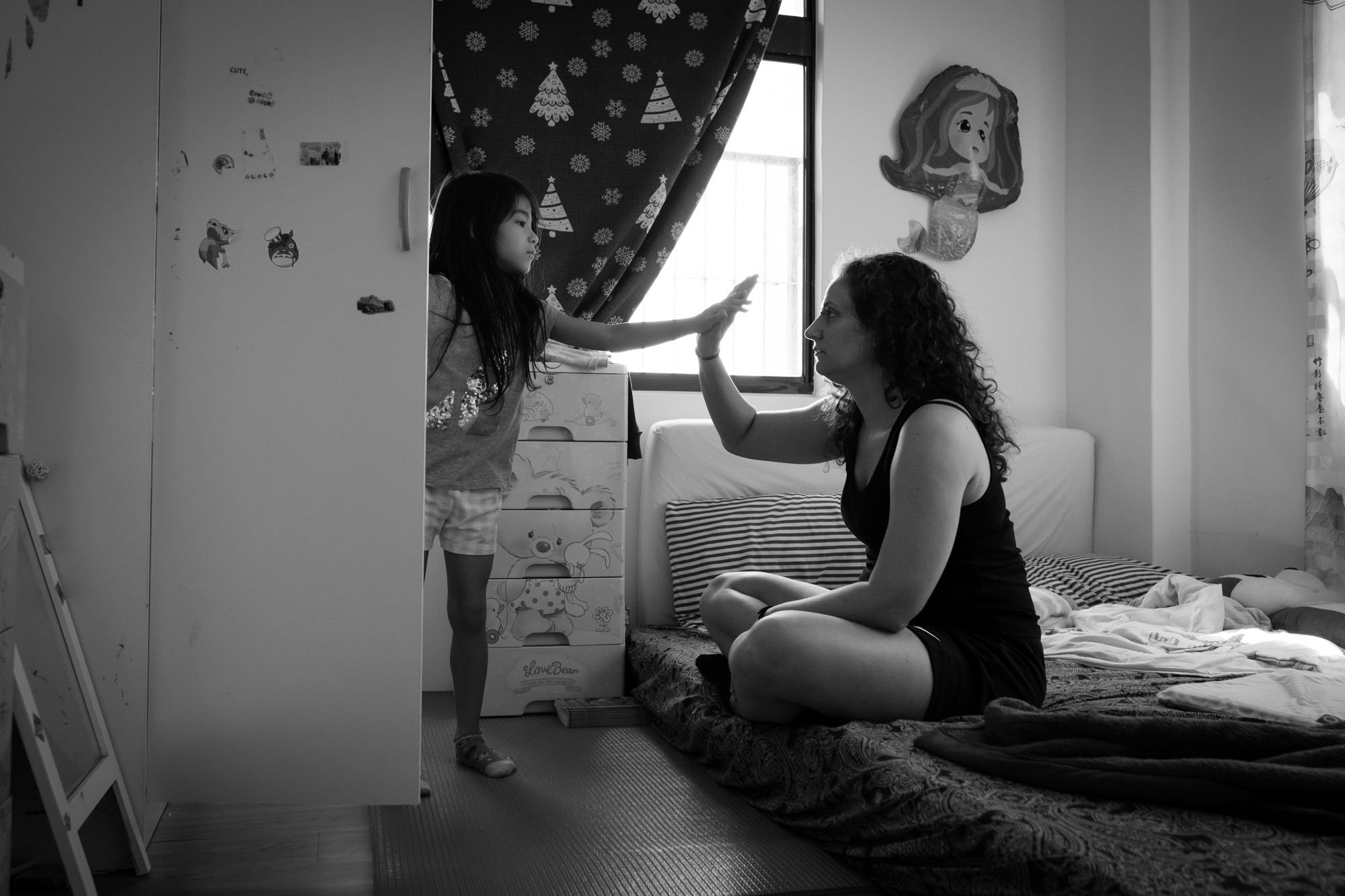 A mother and daughter give each other five in the daughter's bedroom in Taipei, Taiwan.