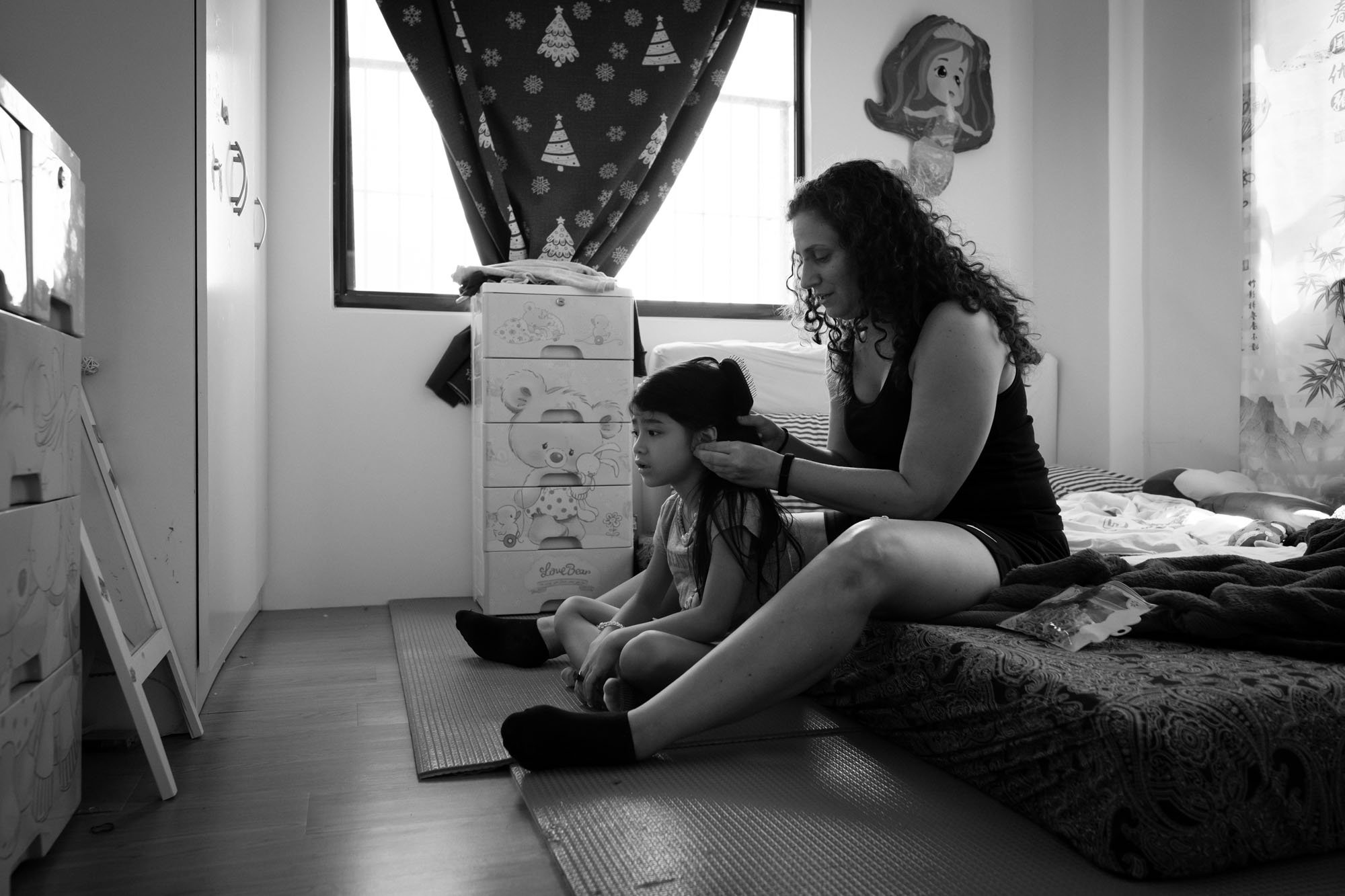A mother plays with her daughters hair in their home in Taipei, Taiwan.