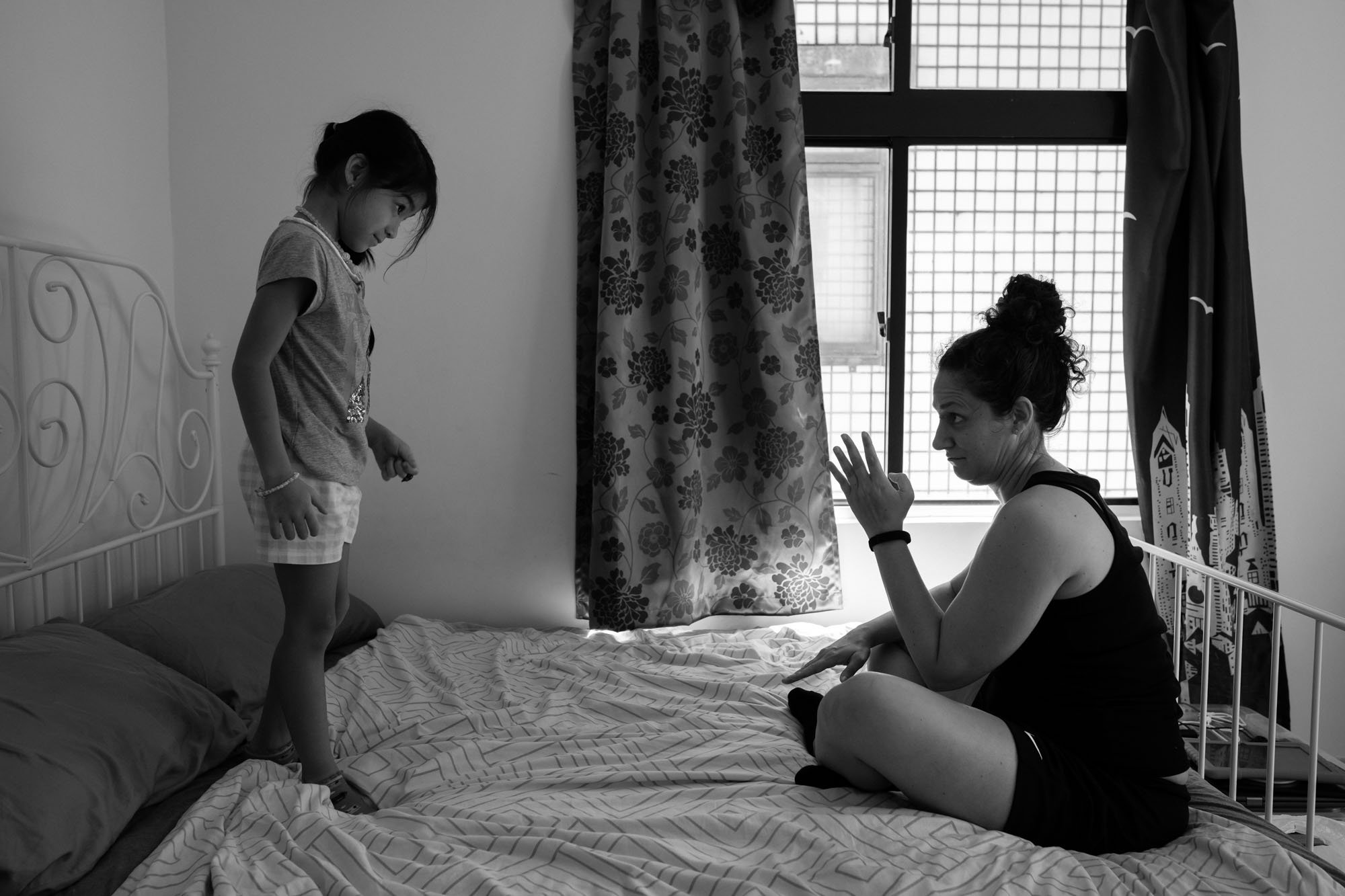 A mother and daughter bow to each other as they're about to start wrestling on their bed in their home in Taipei, Taiwan.