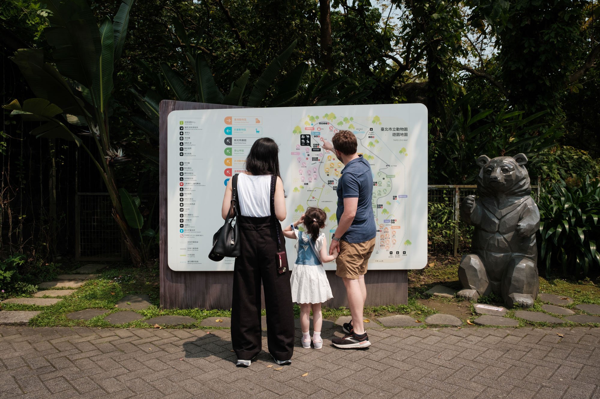 A family looks at a map of the Taipei Zoo together.