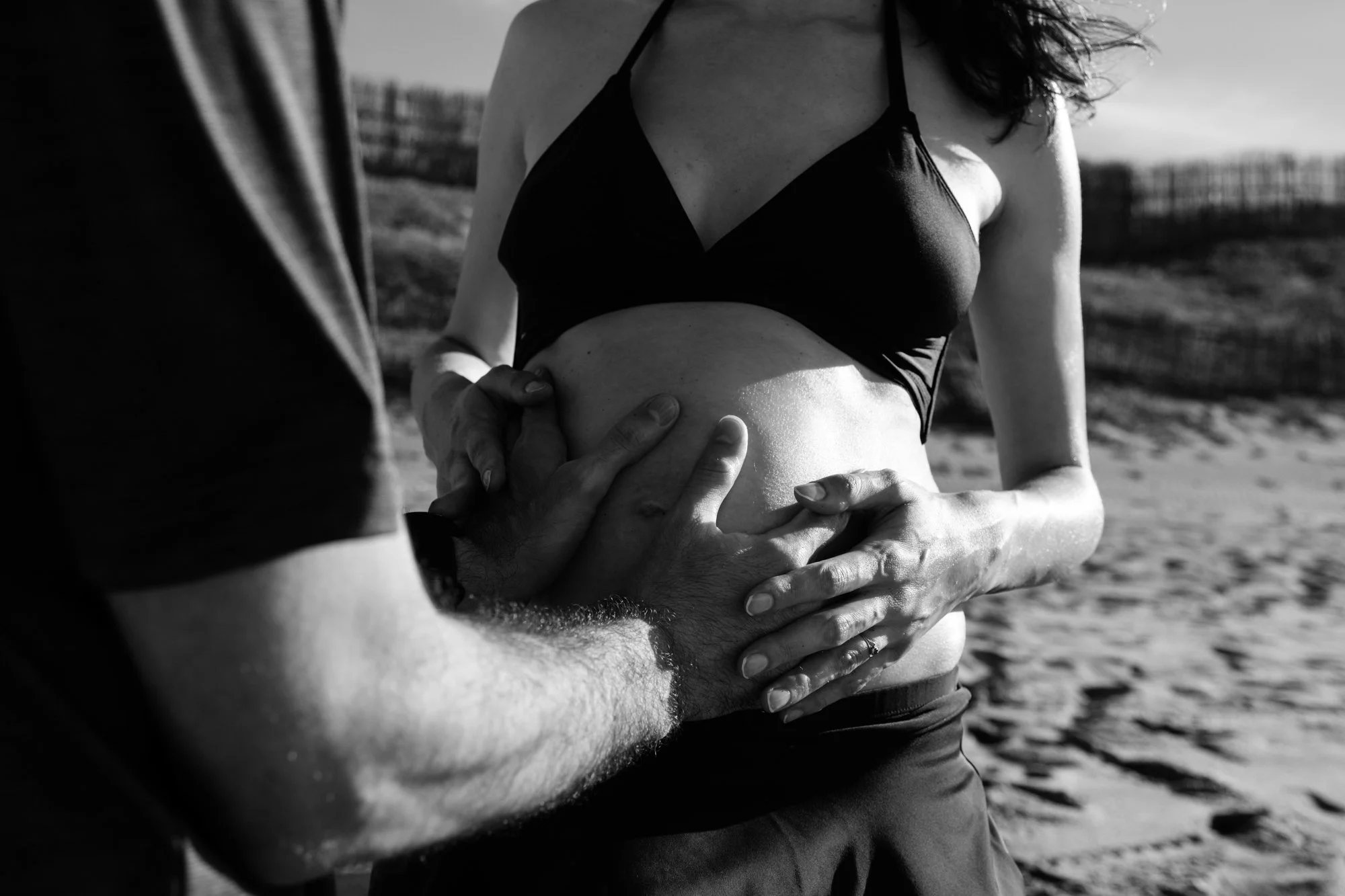 A man put his hands on his wife's pregnant belly at a Baishawan Beach near Taipei. The woman's hands are over the man's hands.