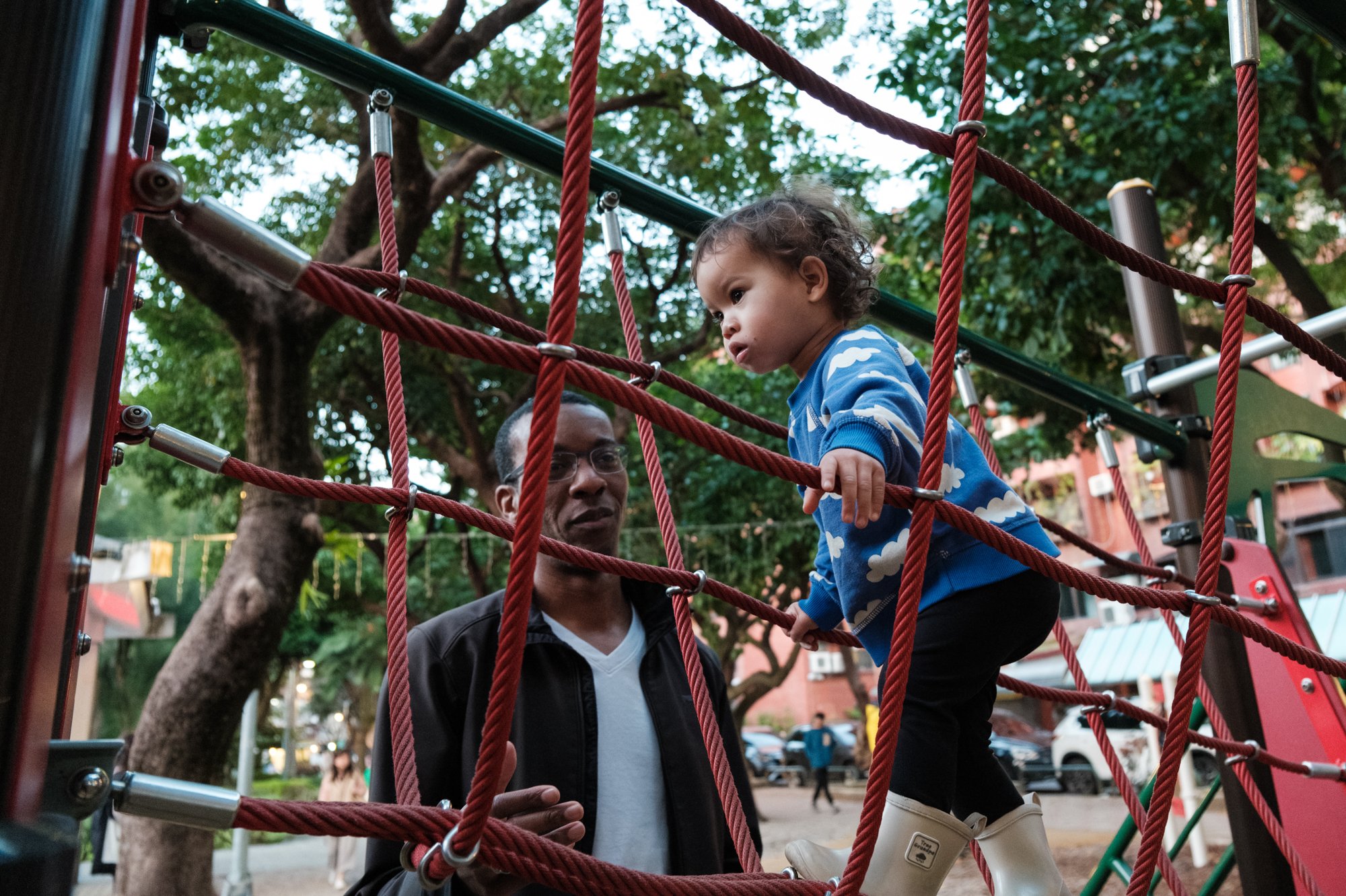 A dad helps his little girl on some playground equipment at a park in Taipei. Photographed by Taiwan family photographer Cahleen Hudson.