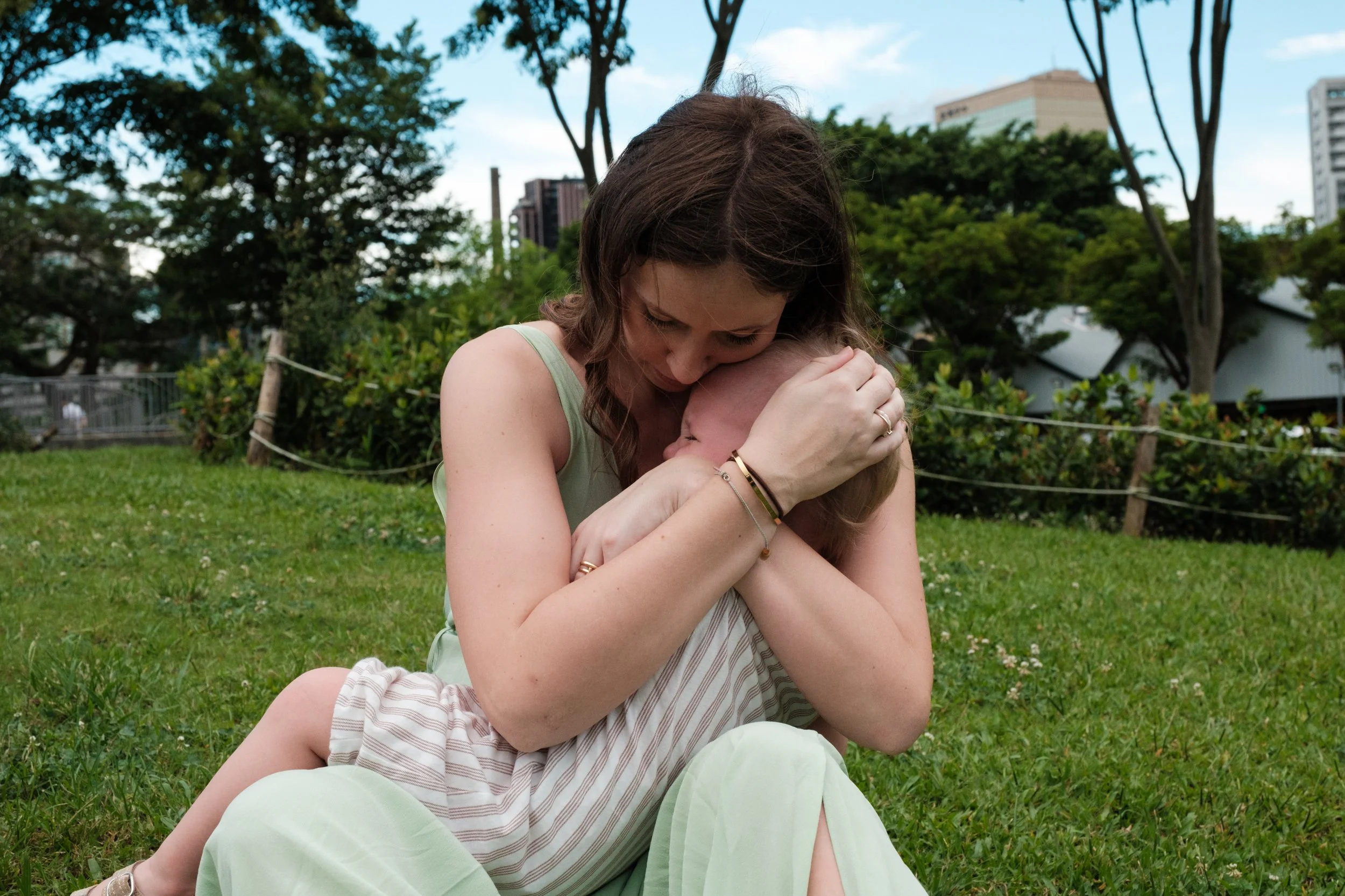 A color image of a mother holding and comforting her crying son at Huashan Creative Park in Taipei. Photographed by family photographer Cahleen Hudson.