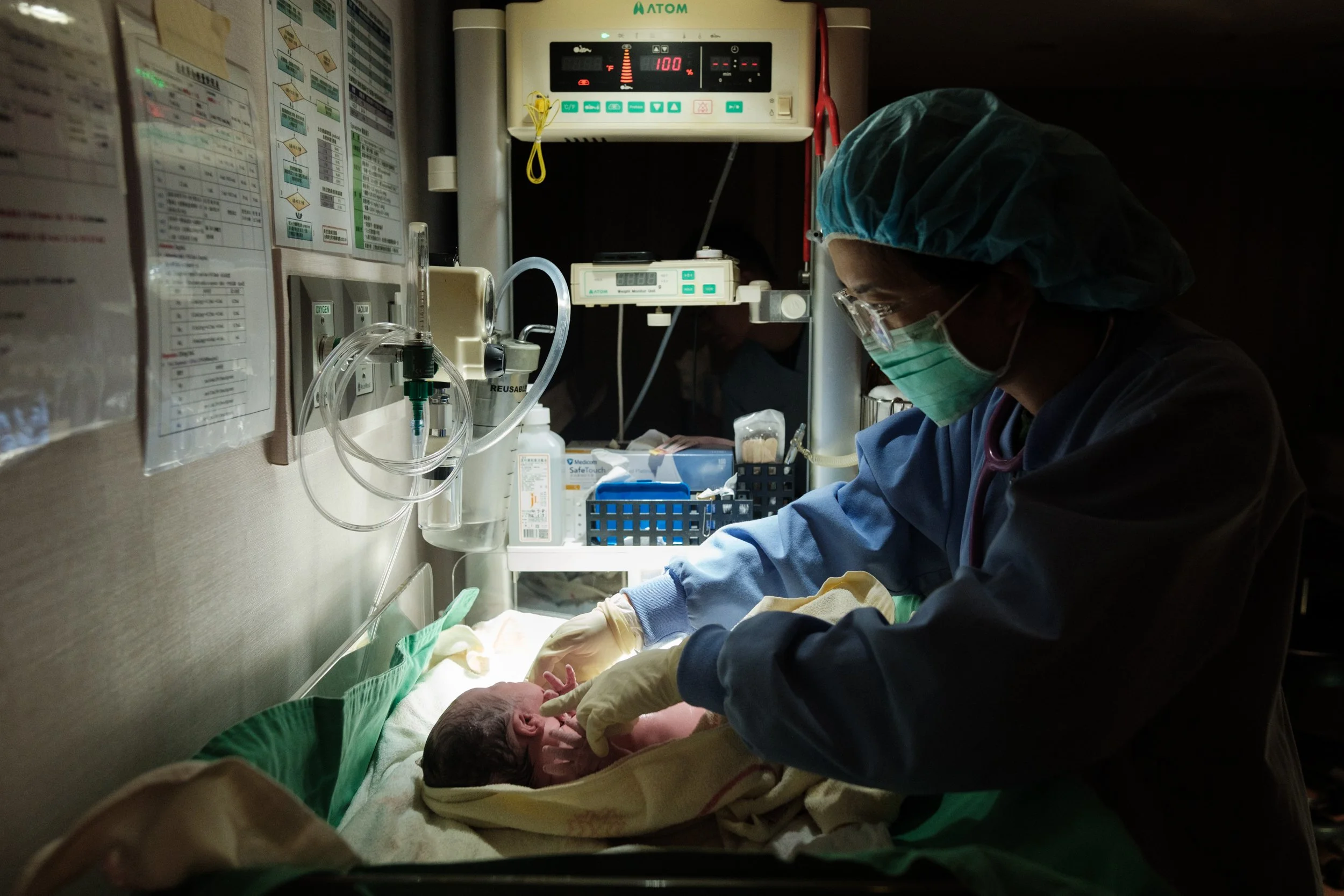 A color photo of a nurse giving a baby their newborn exam at Dianthus in Taipei. Photographed by Taipei birth photographer Cahleen Hudson.