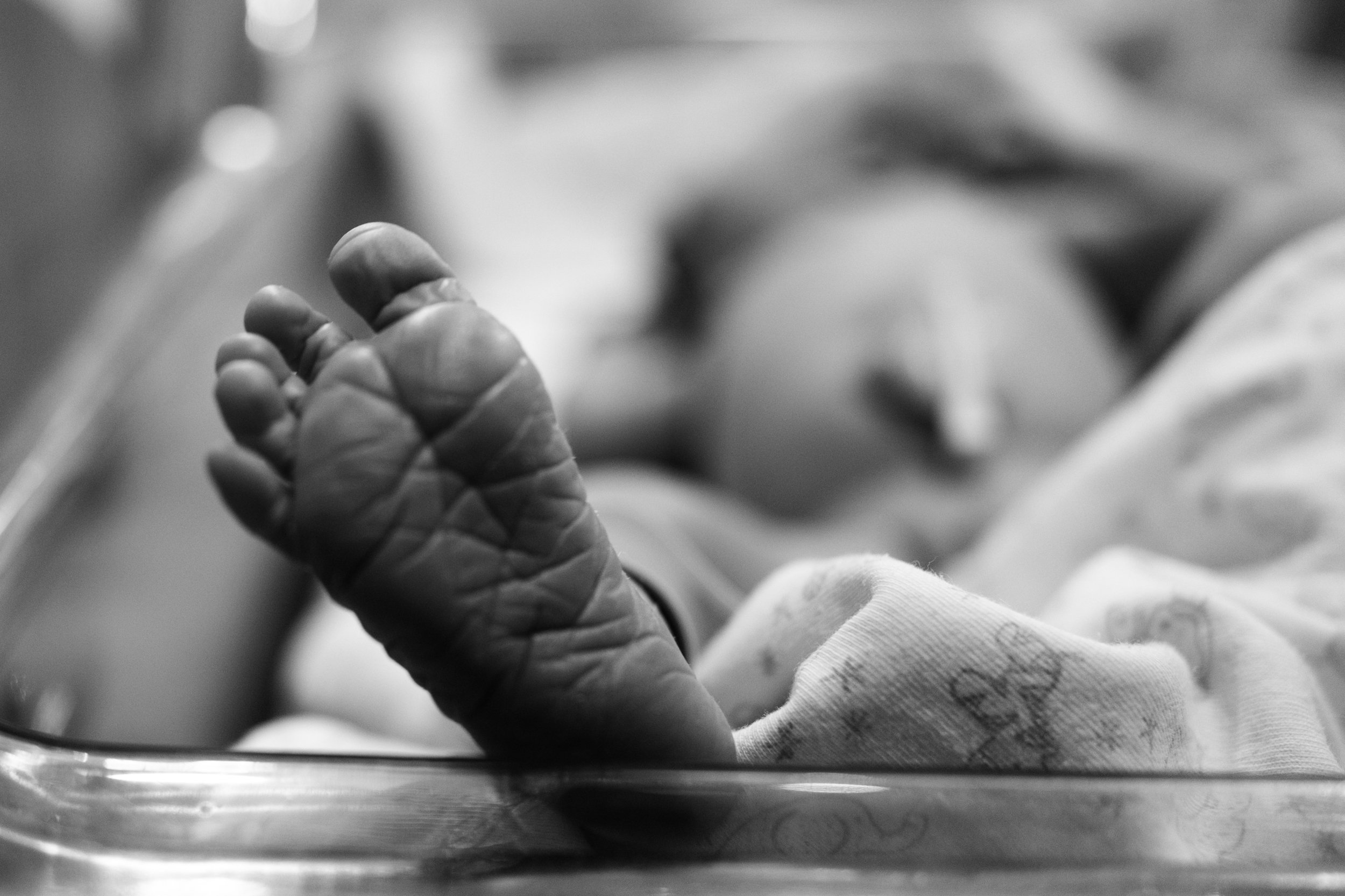 A black and white close-up shot of a newborn baby's foot. The baby is lying in it's bassinet at Dianthus in Neihu.