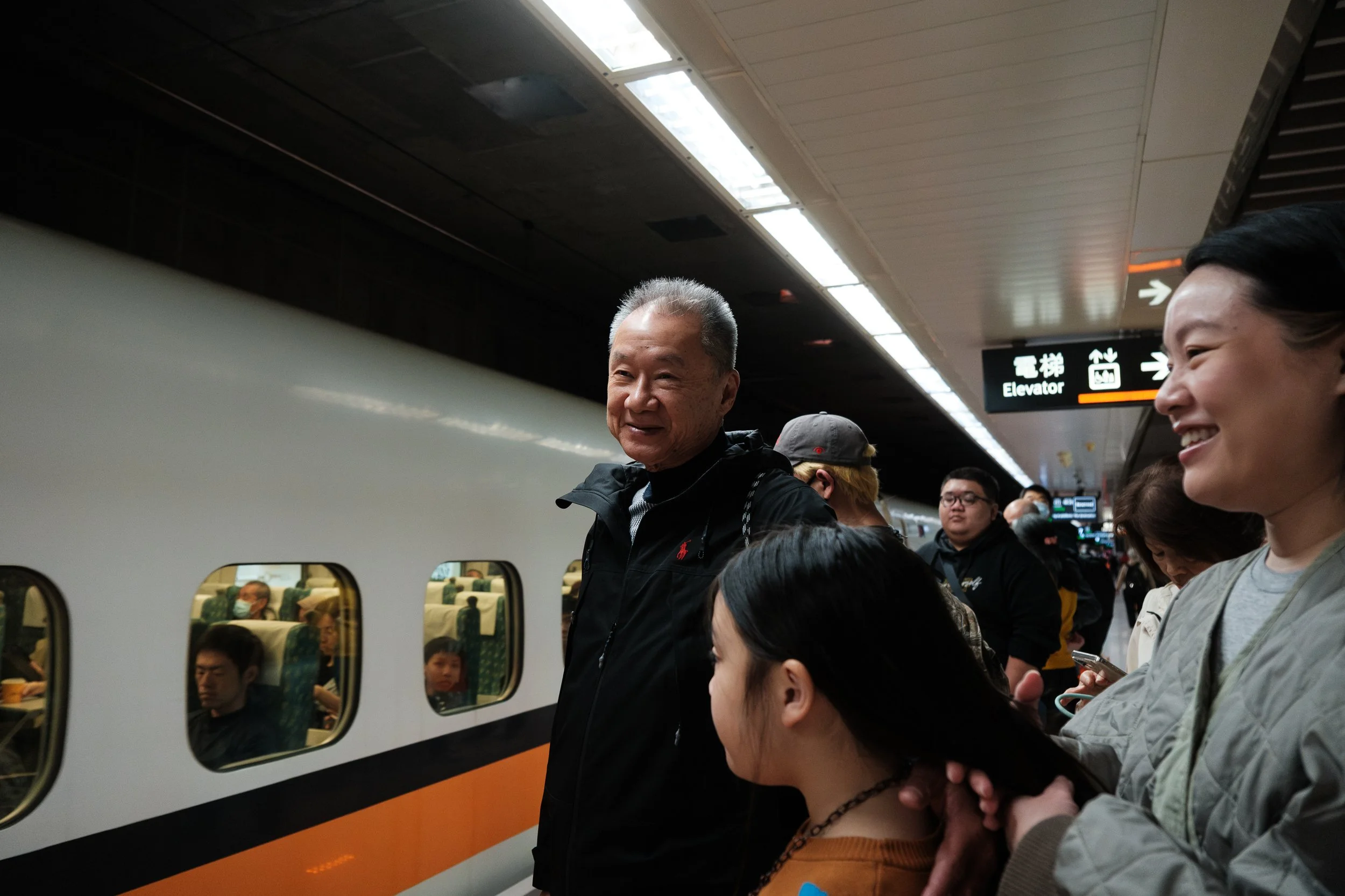 A family waits on the HSR platform in Taipei as a train pulls up. They are traveling to Tainan for a documentary family photoshoot.