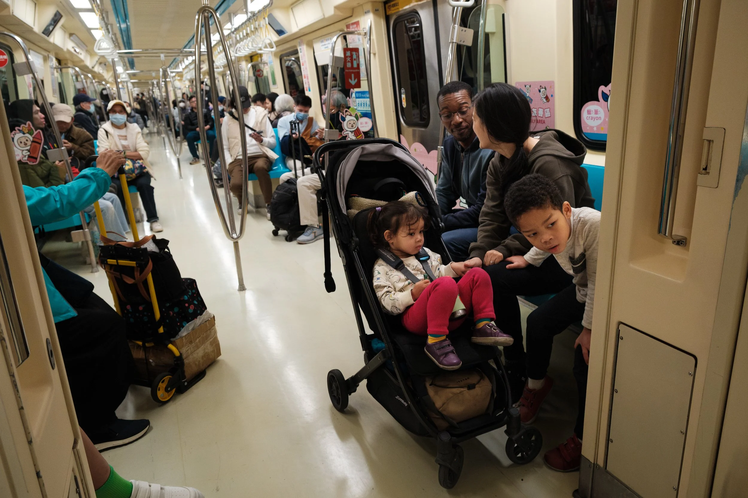 A family of four is riding the MRT during a Taipei family photography session with Cahleen Hudson. 