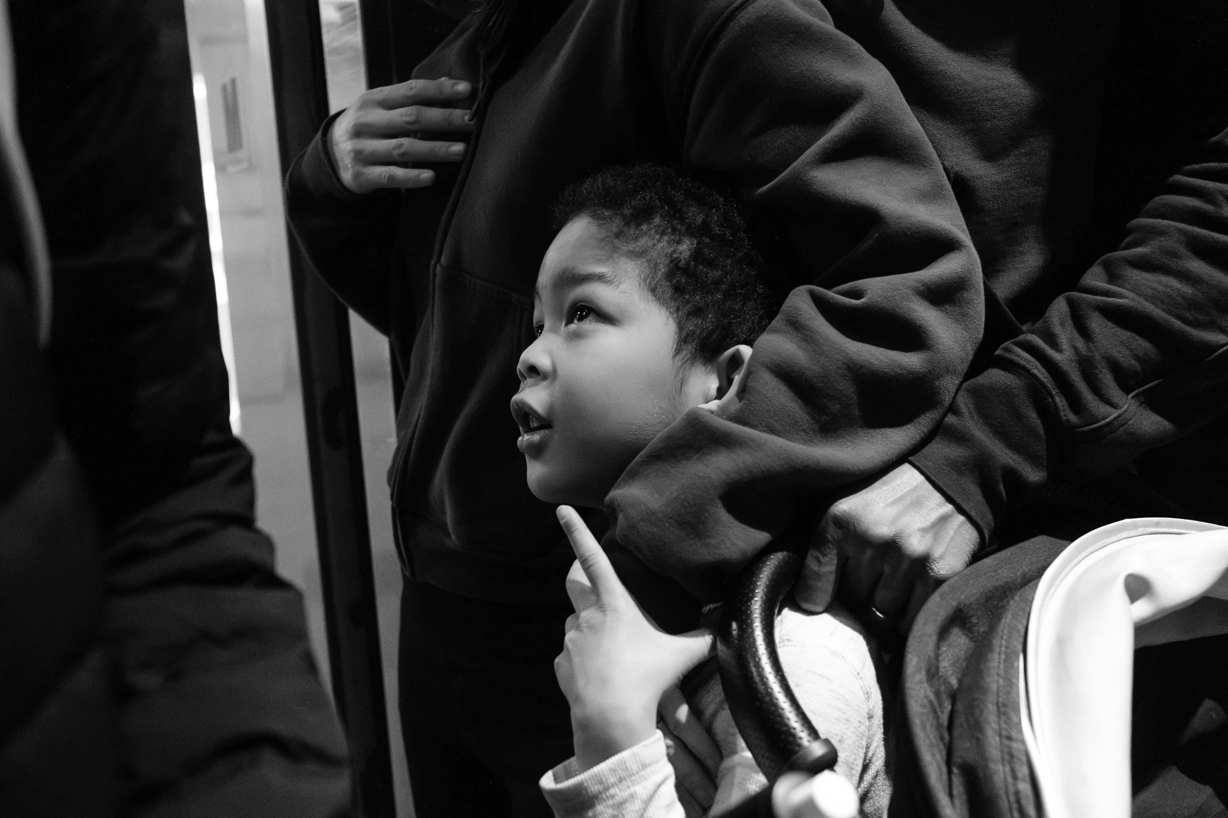 A parent has their arm around a little boy is the take the elevator down to an MRT platform during a Taipei family photoshoot.
