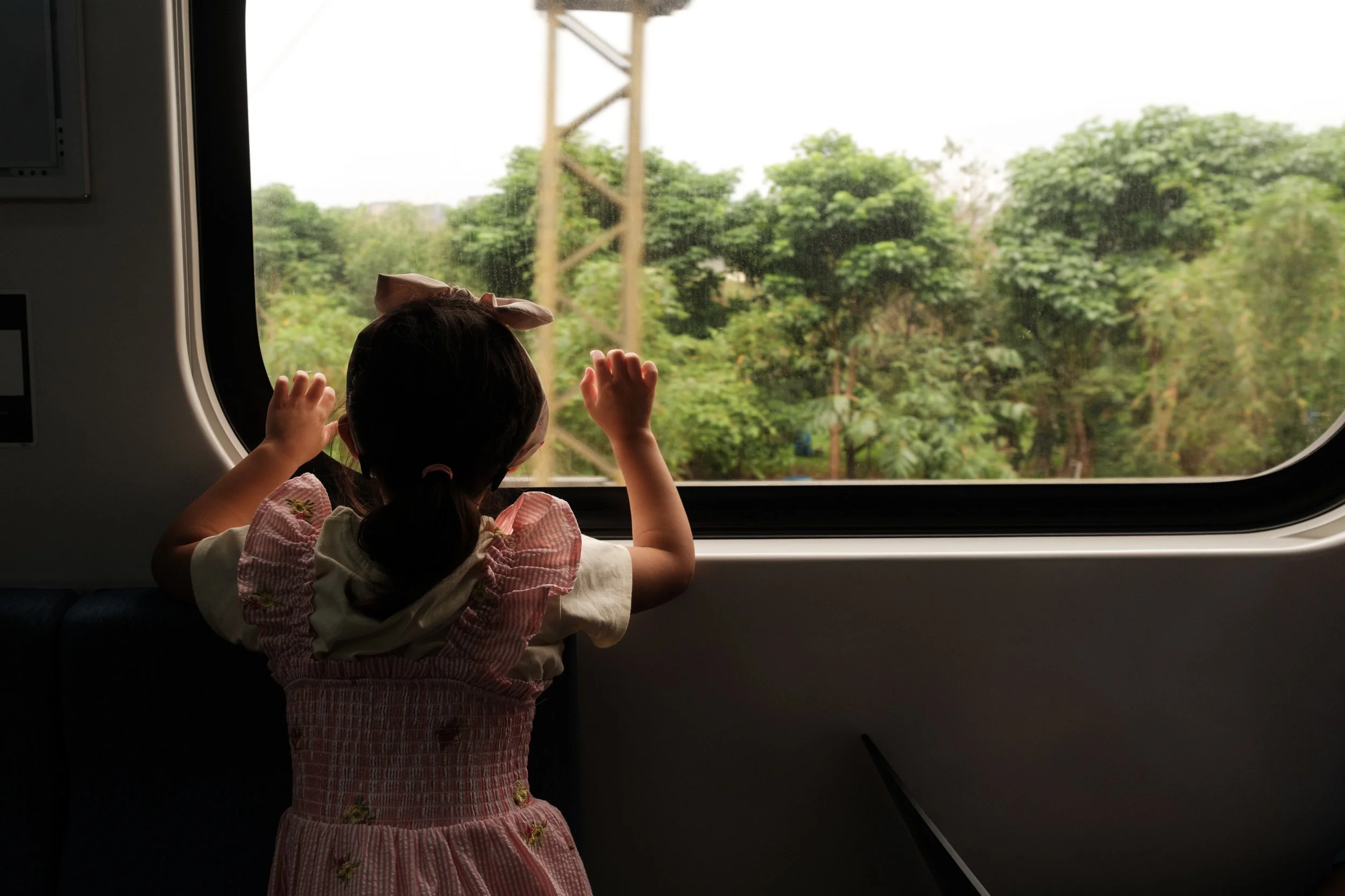 A young girl looks out the window as she rides a train from Taipei to Yingge during a documentary family photography session in Taiwan.