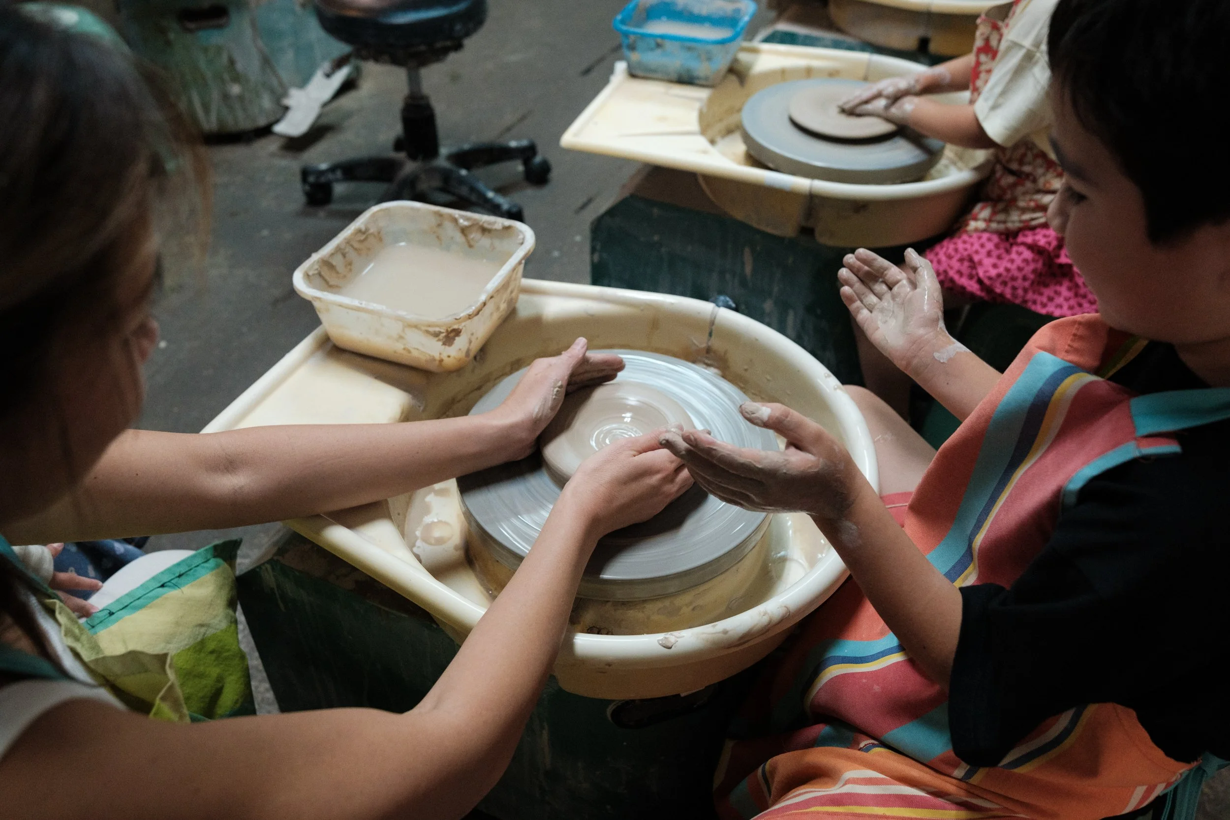 A mother and son are making a clay bowl on a pottery wheel during a DIY class in Yingge. Photographed by taipei documentary family photographer Cahleen Hudson.