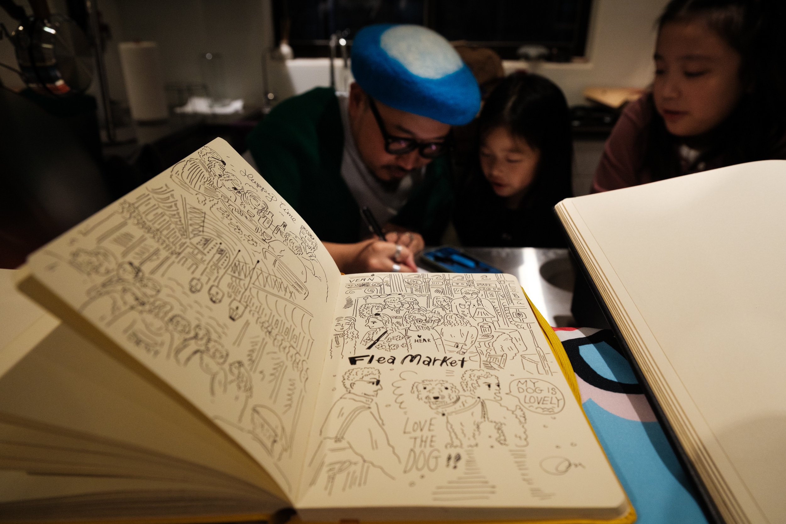A man is doing drawings for people at a drawing station at a gilr's 9th birthday party in Taipei.
