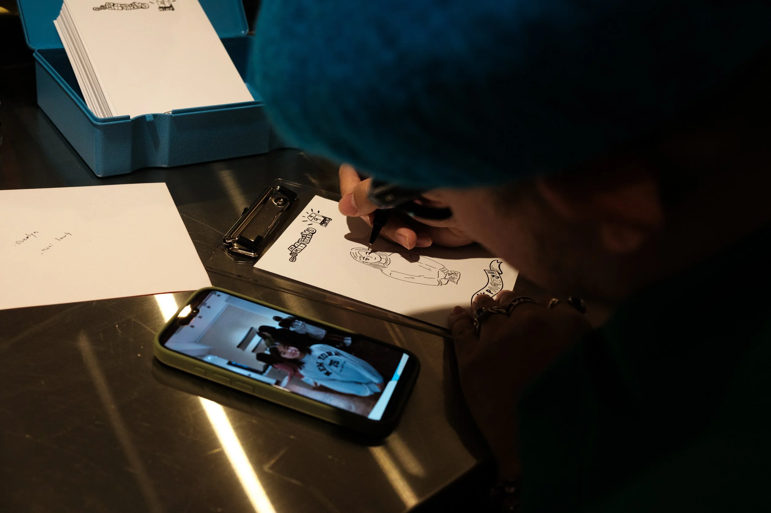 A close-up shot of an artist working on a drawing at the drawing station of a little girl's 9th birthday party in Taipei. Photographed by documentary family photographer Cahleen Hudson.