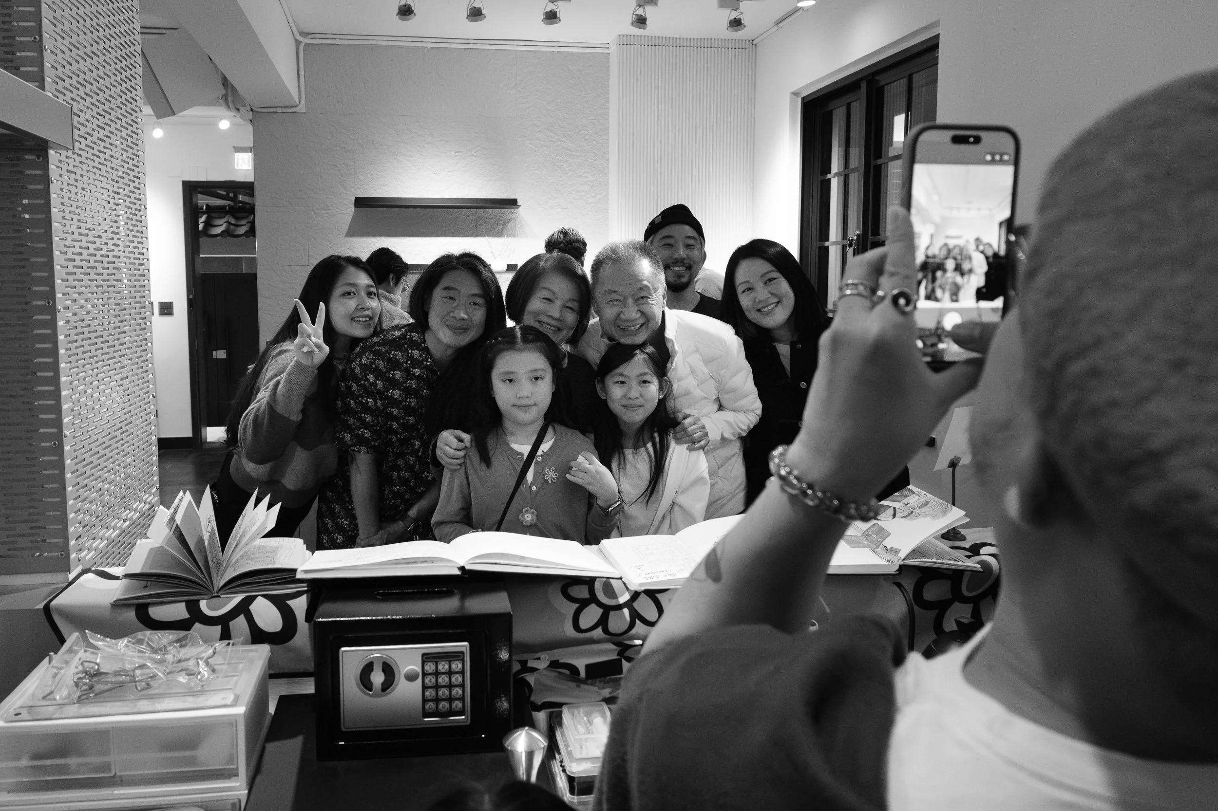 A man running a drawing station at a child's birthday party in Daan, Taipei photographs a family so he can draw a caricature of them.