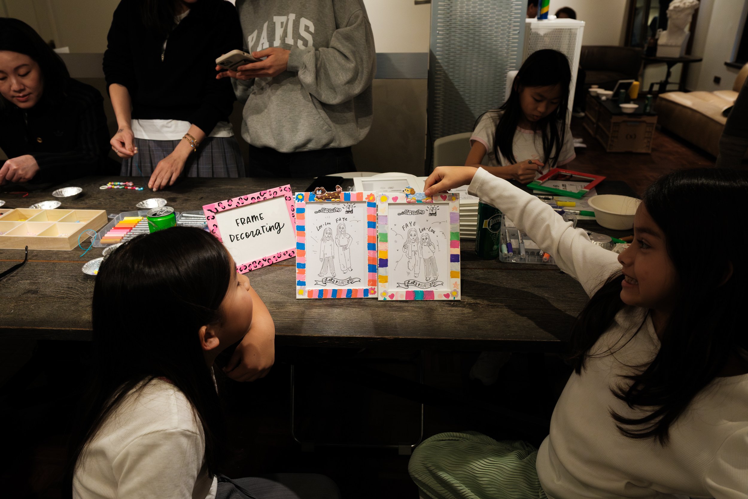 Two little girls are showing off the frames they made at the frame-making station at their friend's 9th birthday party at MRKT5 in Taipei.