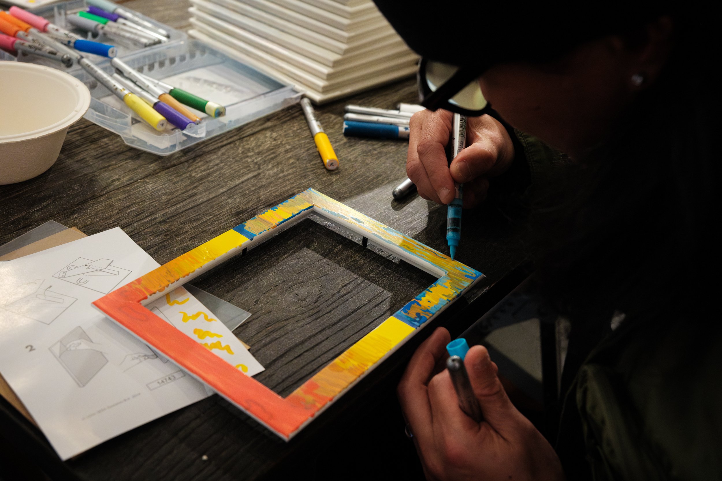 A little girl colors a wooden picture frame with markers at the frame-making station at a child's birthday party in Taipei.