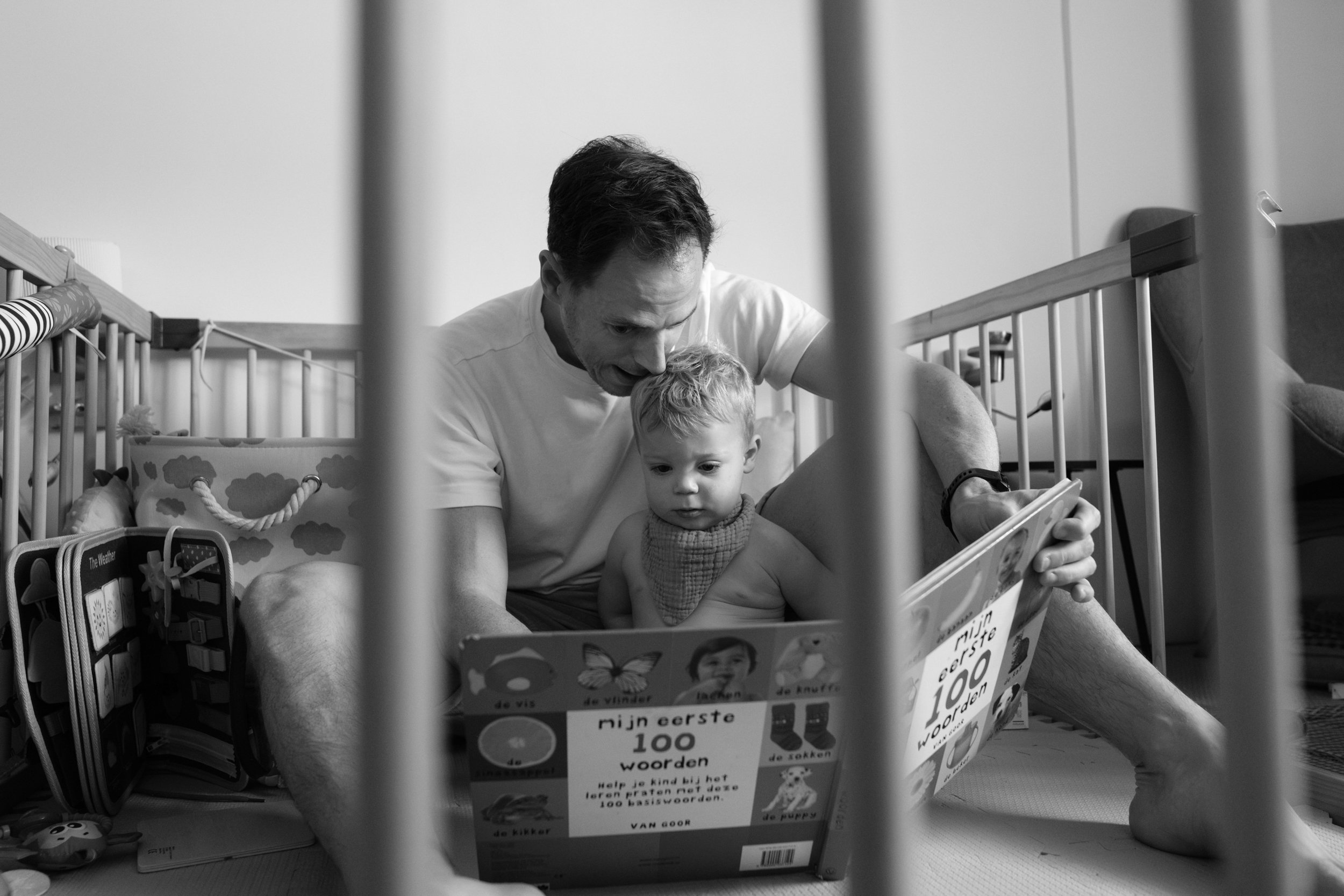 A father reads to his toddler son on the floor of their apartment in Taipei during an indoor family photography session.