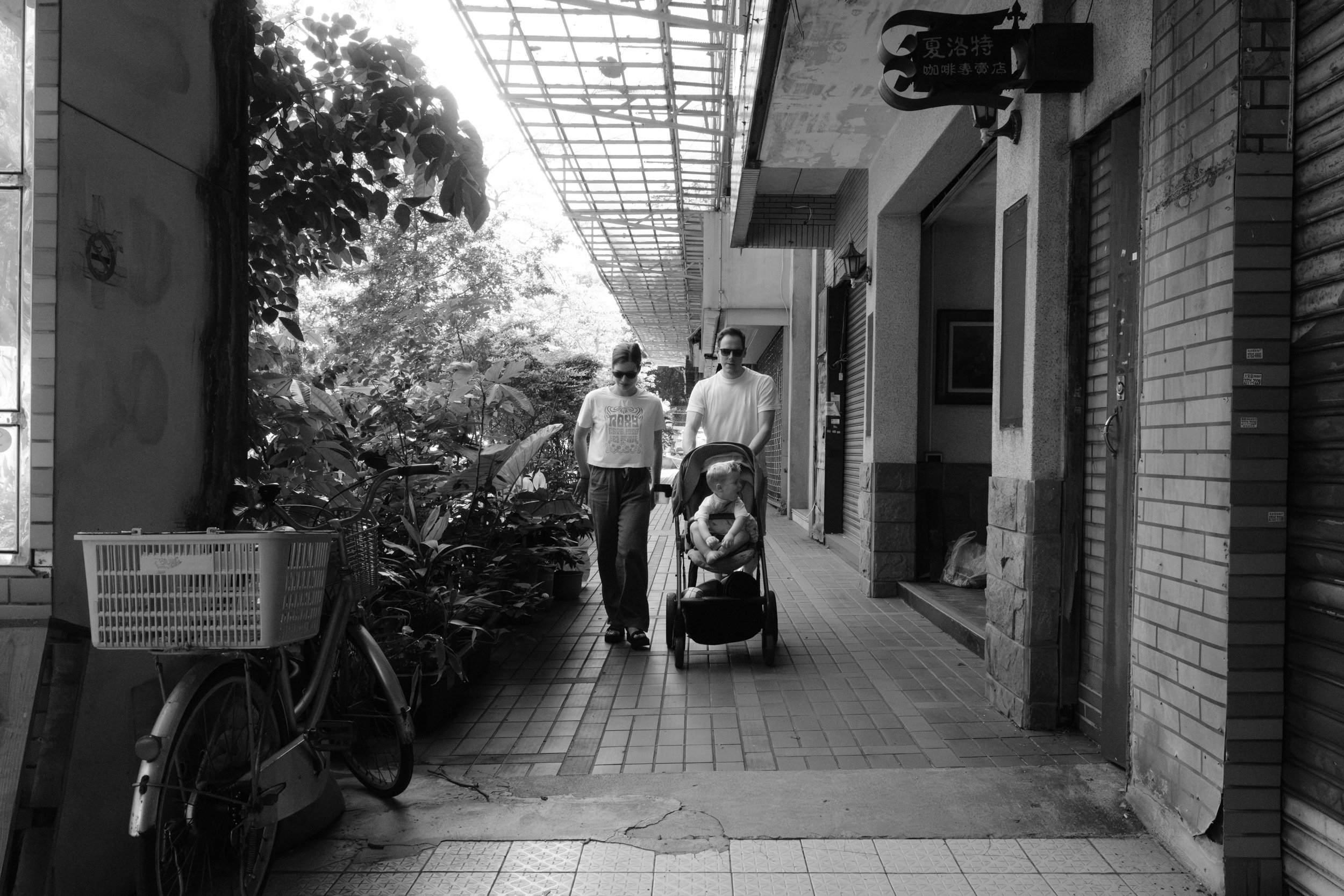 A couple is pushing their toddler son down a Taipei street in his stroller during an outdoor documentary family photography session. 