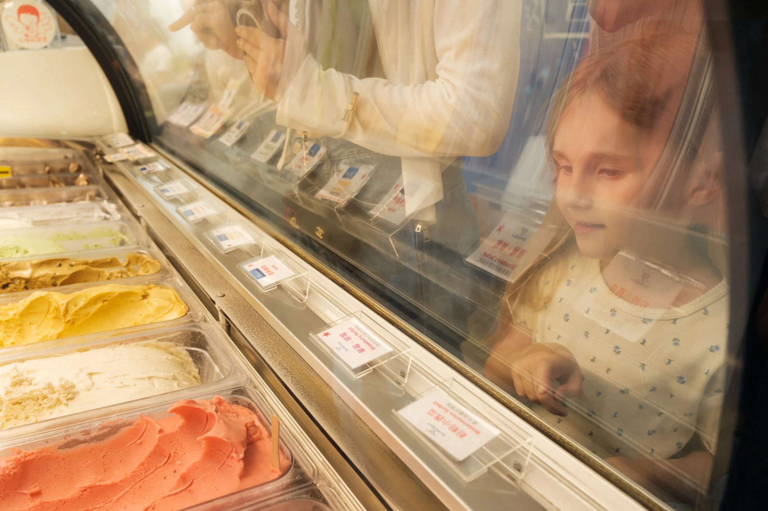 Taipei documentary family photography, Tienmu gelato shop | Young girl studies the flavors through the glass of a neighborhood gelato case