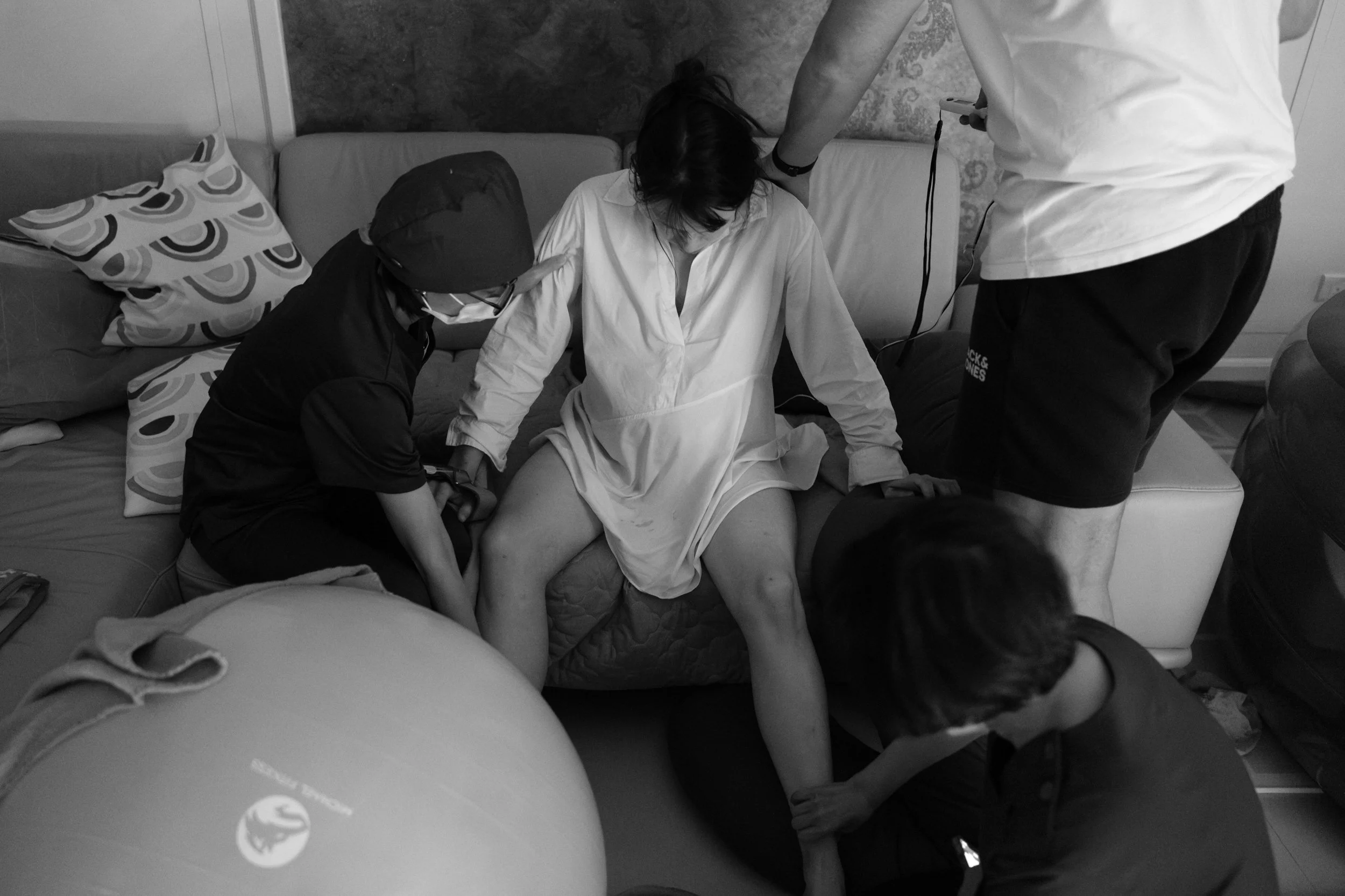 Home birth midwives supporting a mother through a contraction on the couch during a taipei home birth