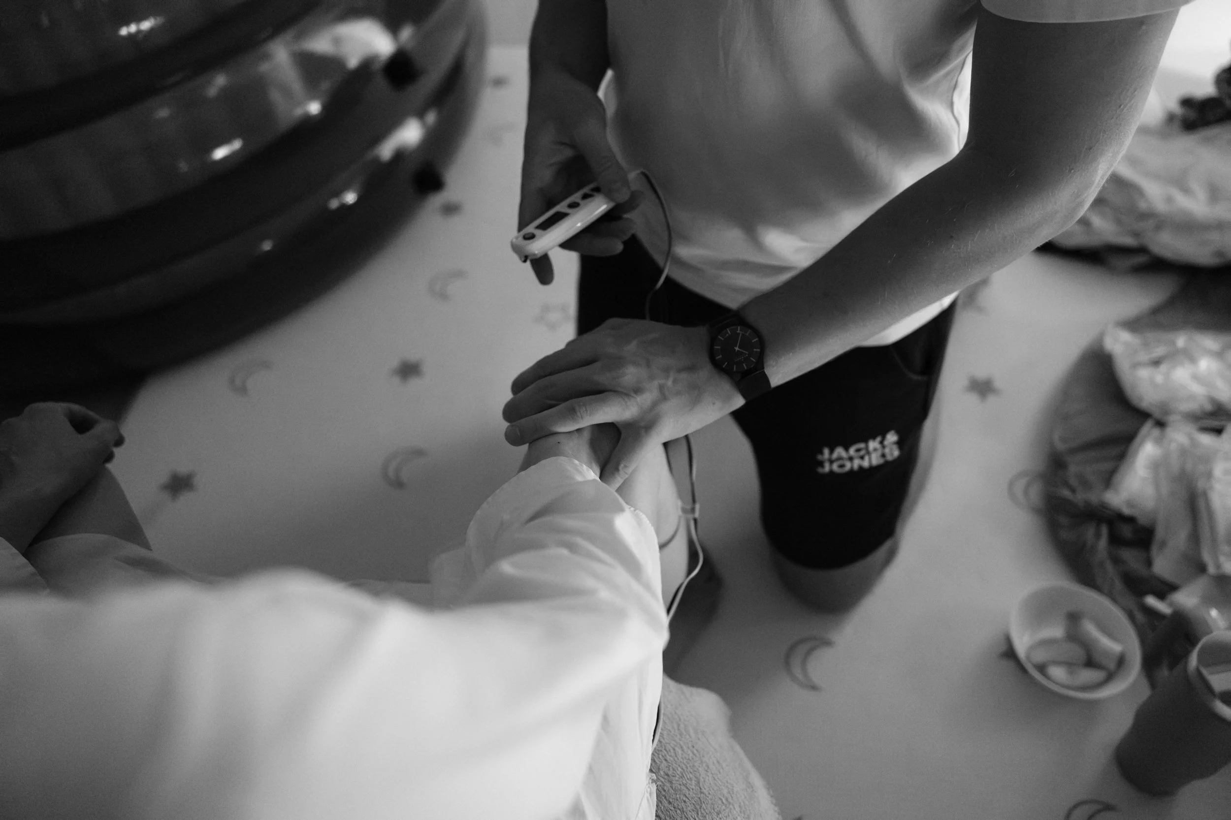 A partner timing contractions while holding a laboring mother's hand during her Taipei home birth