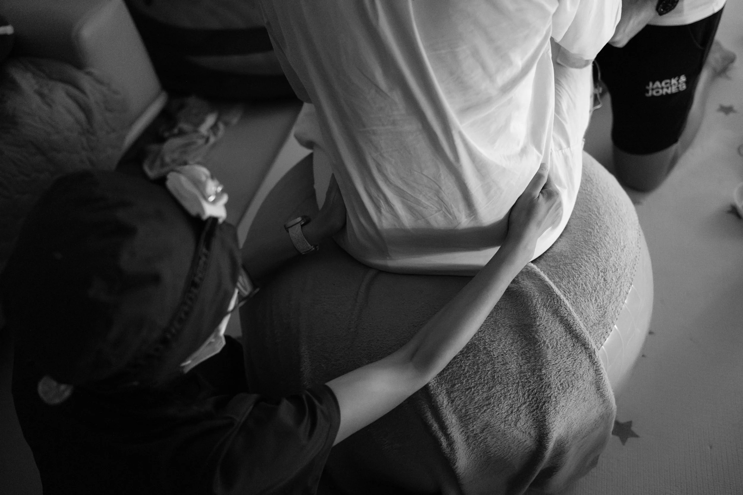 A midwife applying counterpressure to ease hip pain during labor in a home birth in Taipei