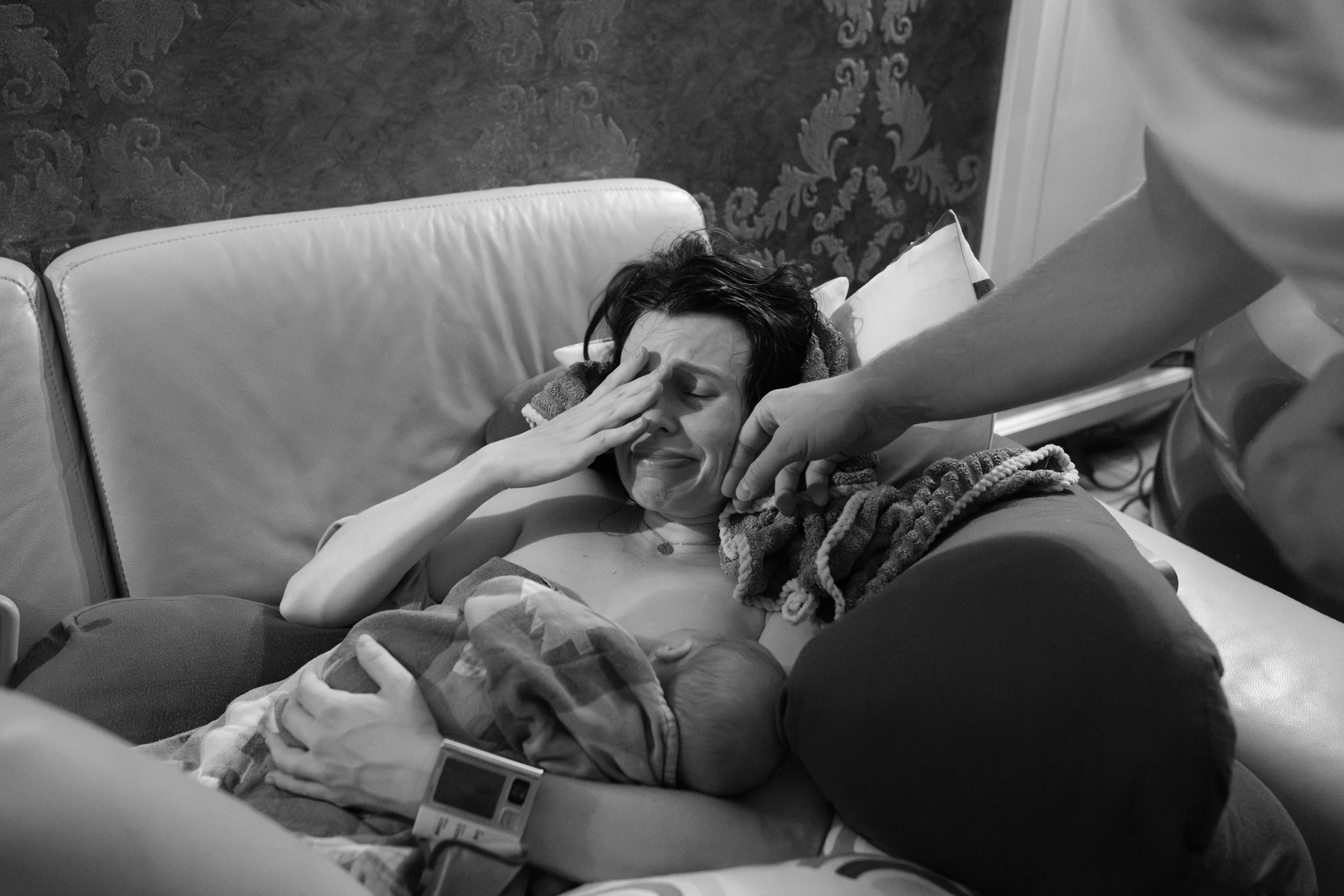 Mother crying tears of joy while holding her newborn for the first time