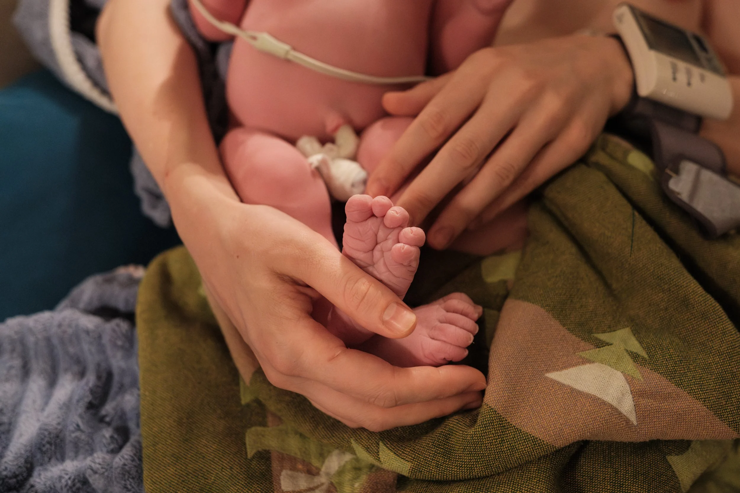 Close-up of a newborn's tiny feet cradled in his mother's hands