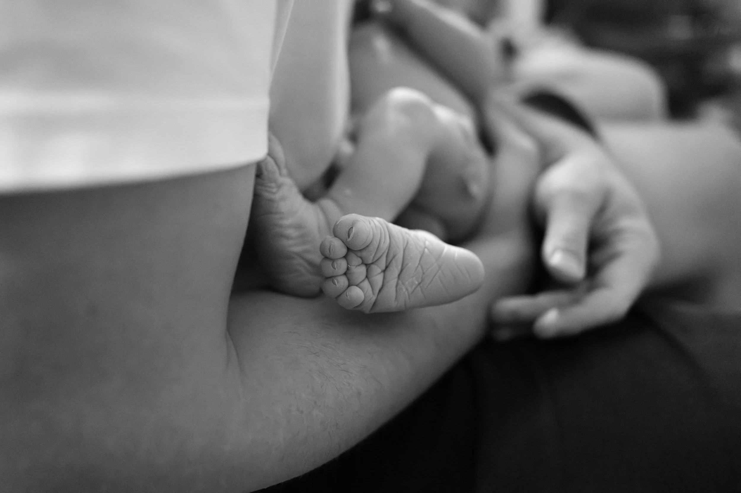 Newborn's foot resting against a parent's arm after a home birth in Taipei