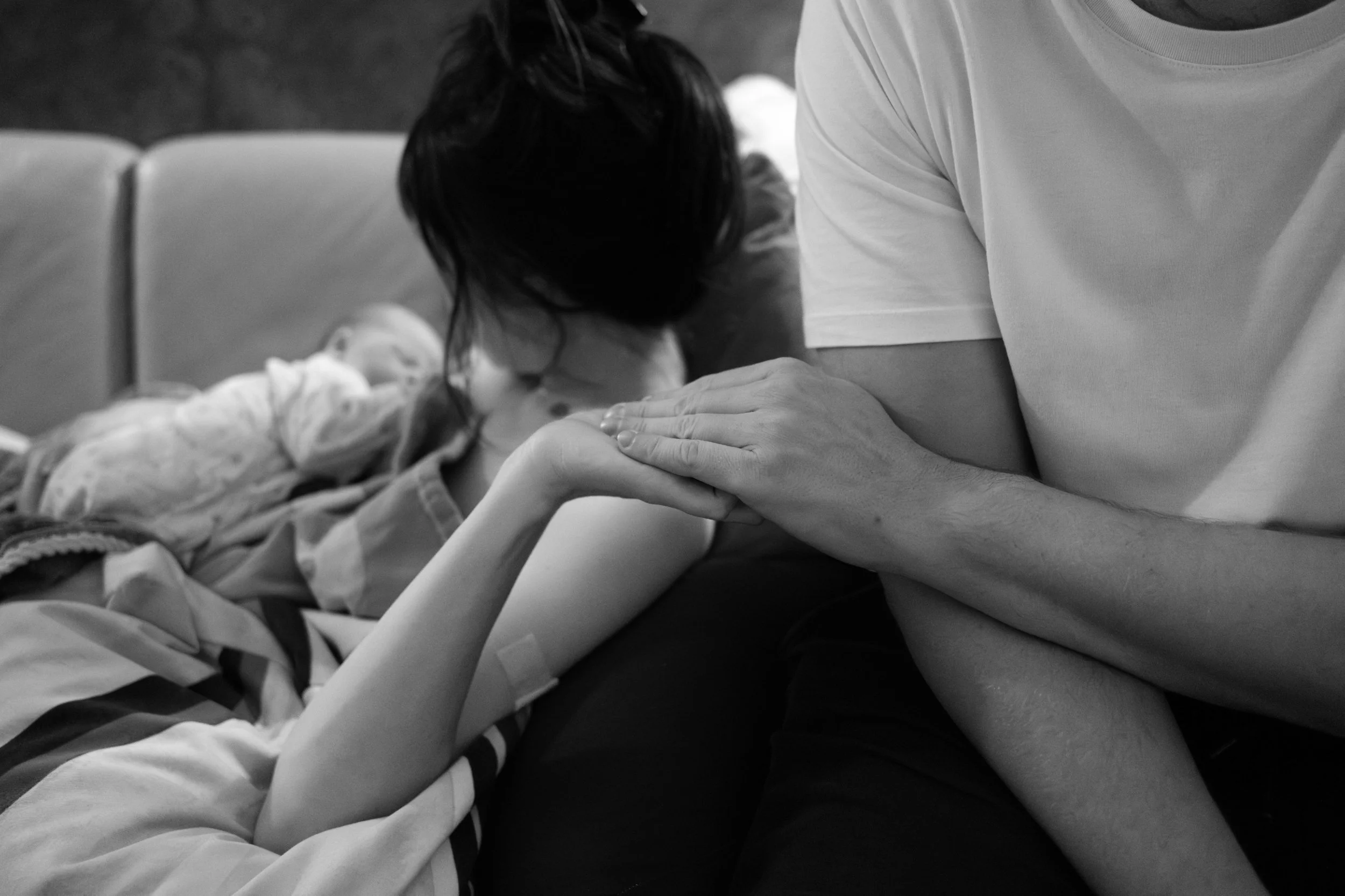 Parents holding hands while mother breastfeeds their newborn after a home birth in Taipei