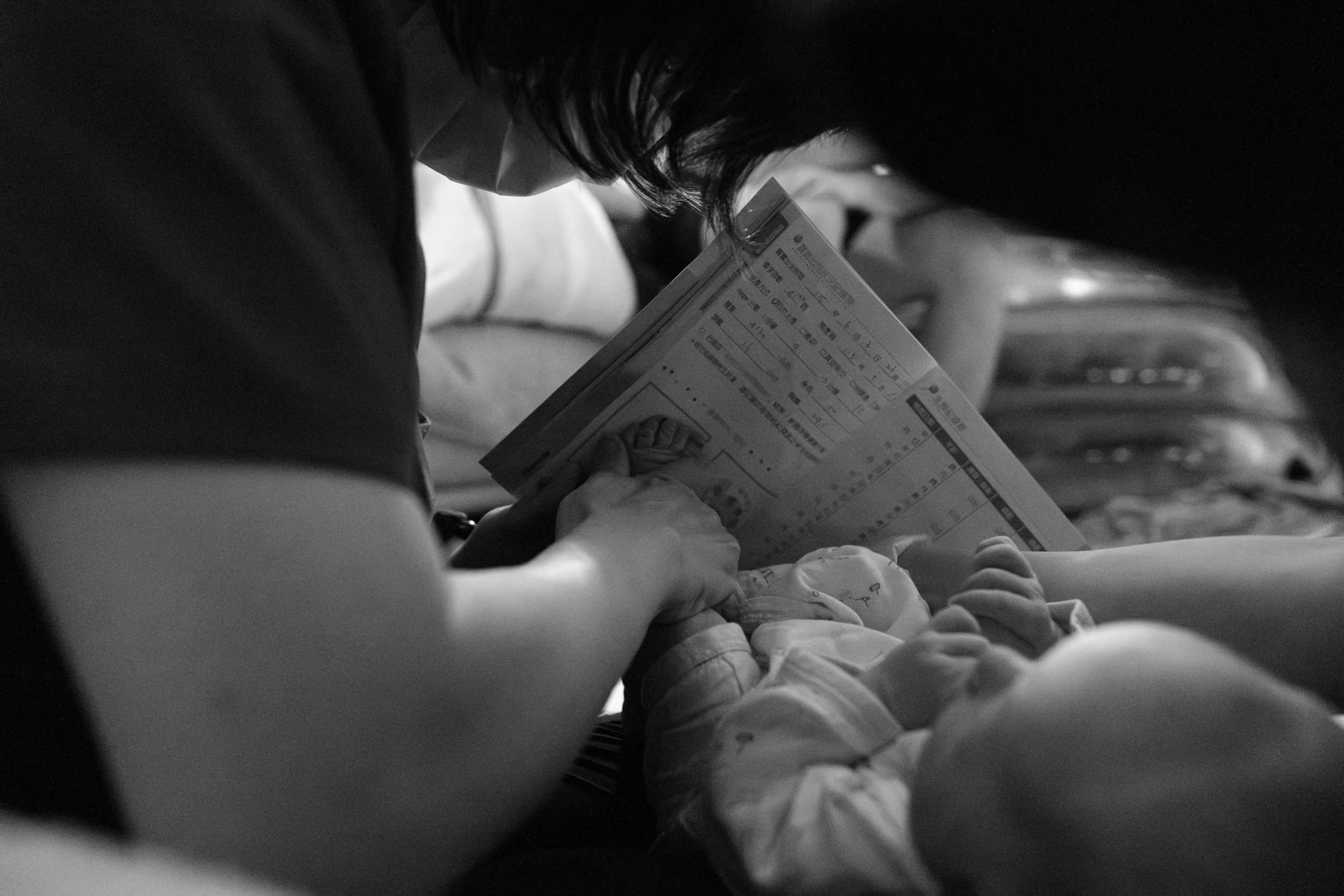 Taipei midwife putting the newborn's footprints in Taiwan's maternal health handbook after a home birth