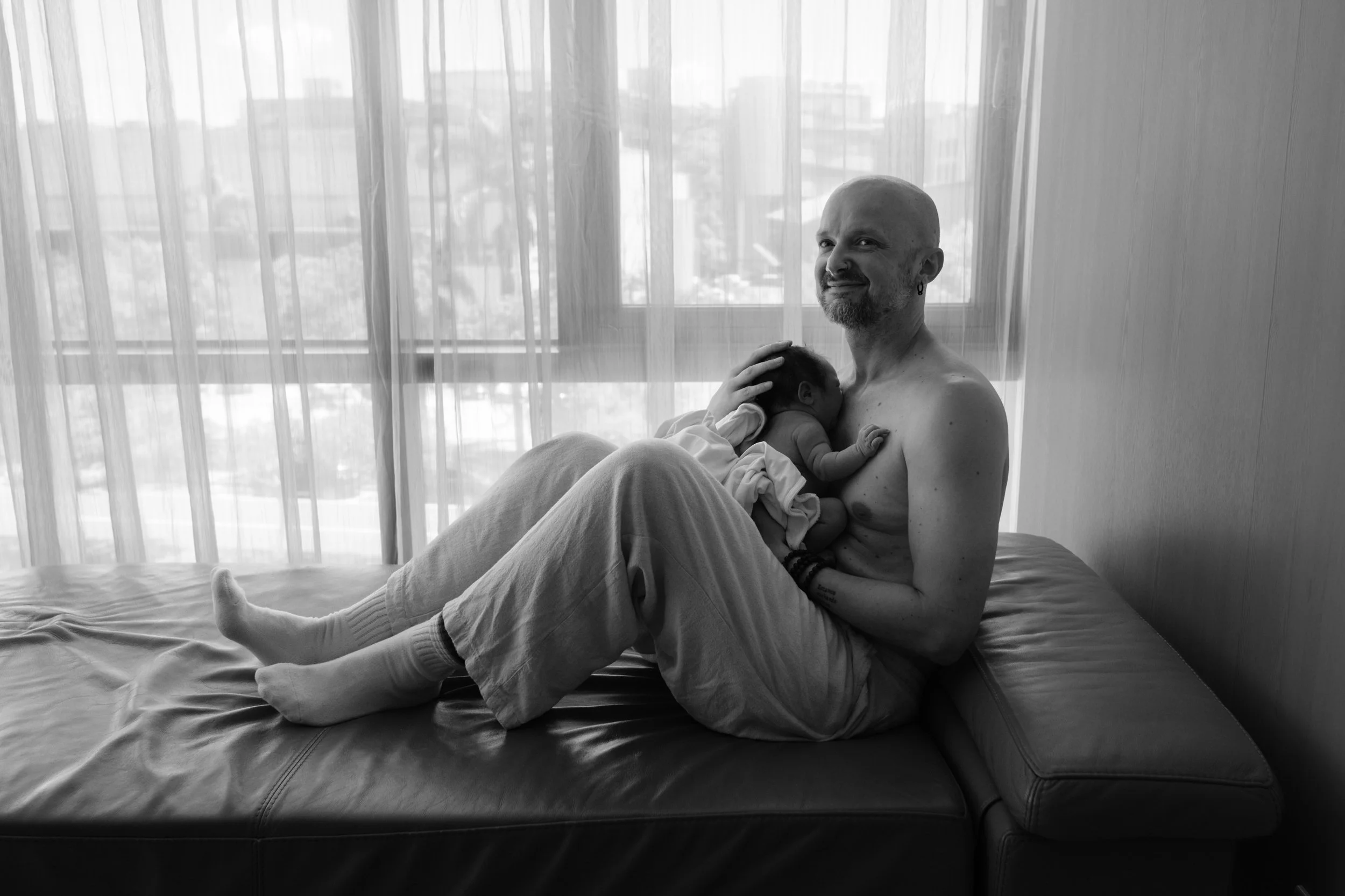 Postpartum portrait from Dianthus, Taipei — father cradling his newborn by the window.