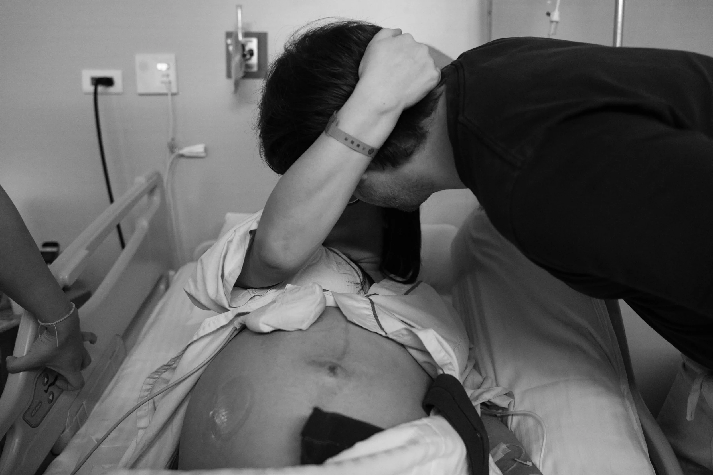 C-section birth photography in Taipei — partner rests head against mother's shoulder in a tender moment before delivery.