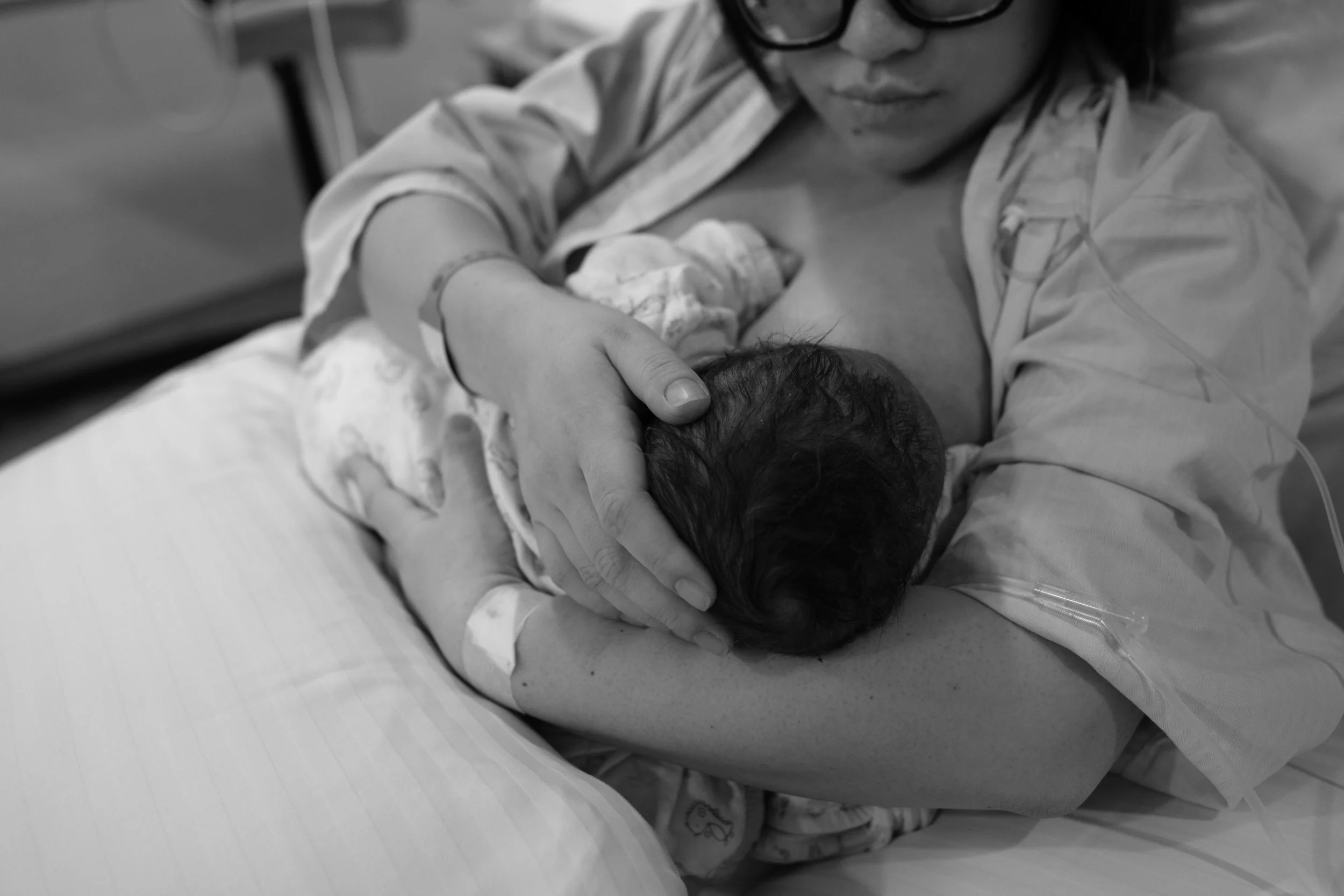 Documentary birth photography Taipei — close-up of mother breastfeeding her newborn after c-section birth.