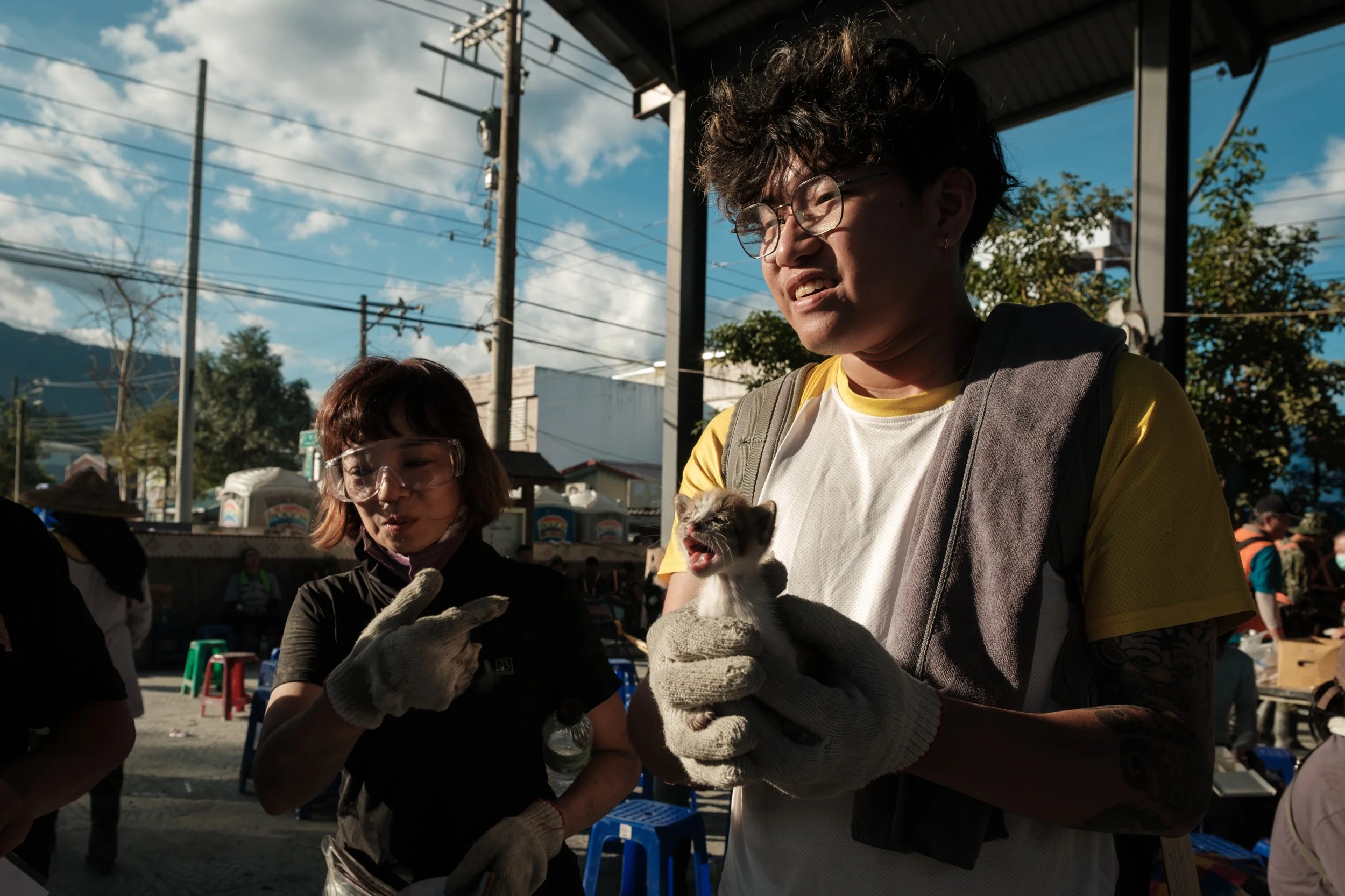 Two volunteers who are aiding in the Guangfu flood recovery efforts are holding a small kitten that they found among the wreckage. 