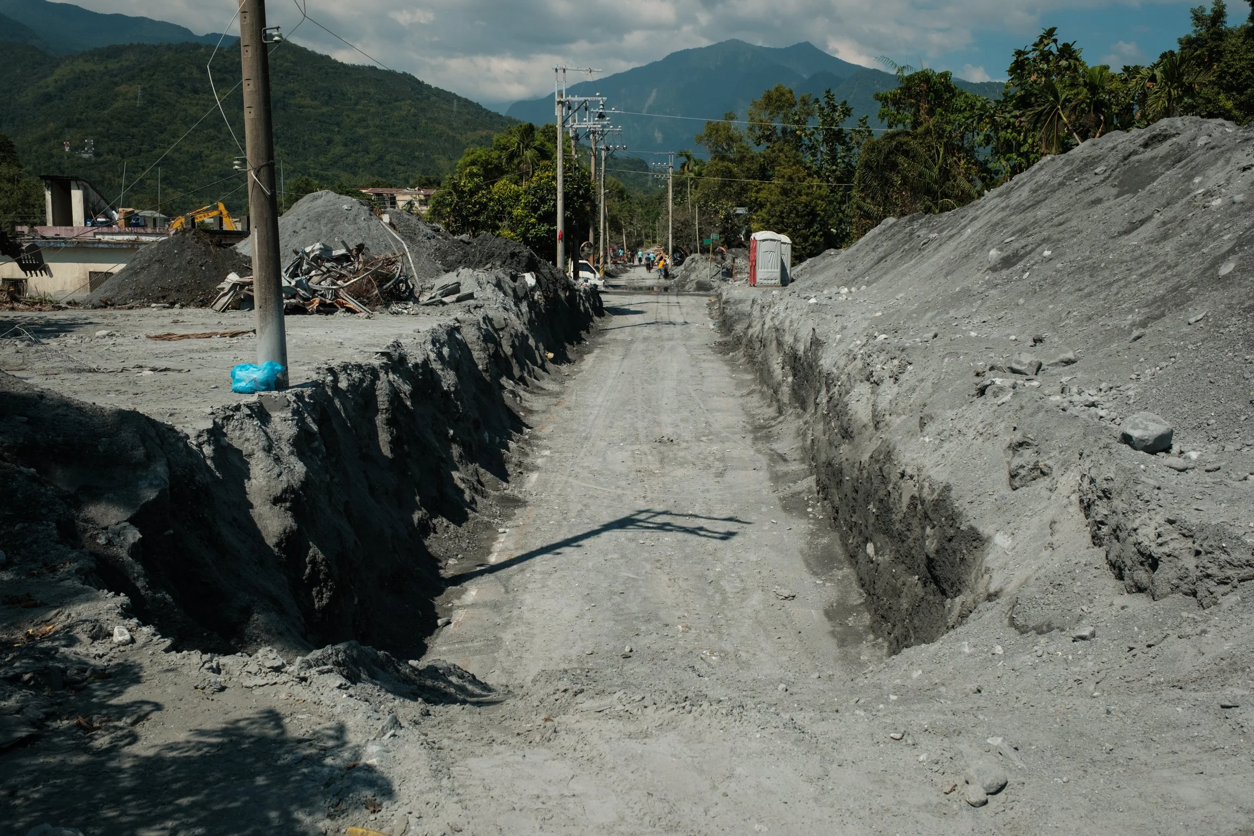 A sliver of road has been carved out from the mud after the Guangfu flooding in Hualien, Taiwan. You can see walls of mud on either side of the road.