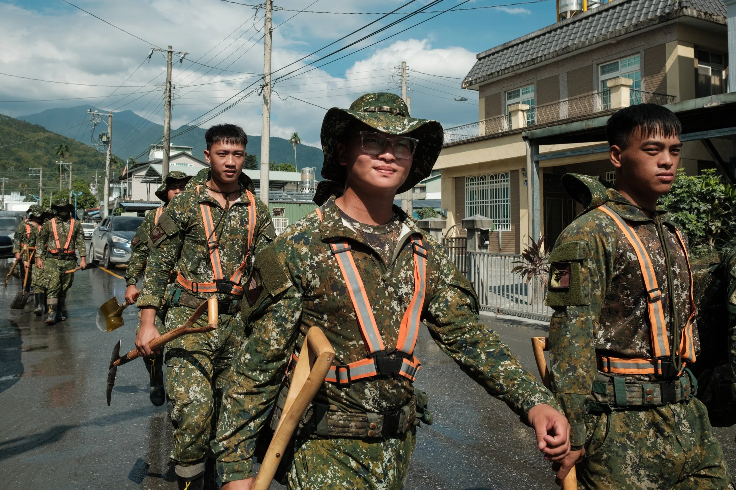 A group of Taiwanese soldiers that have been sent down to aid in the Guangfu flood recovery efforts can be seen marching down a muddy street.