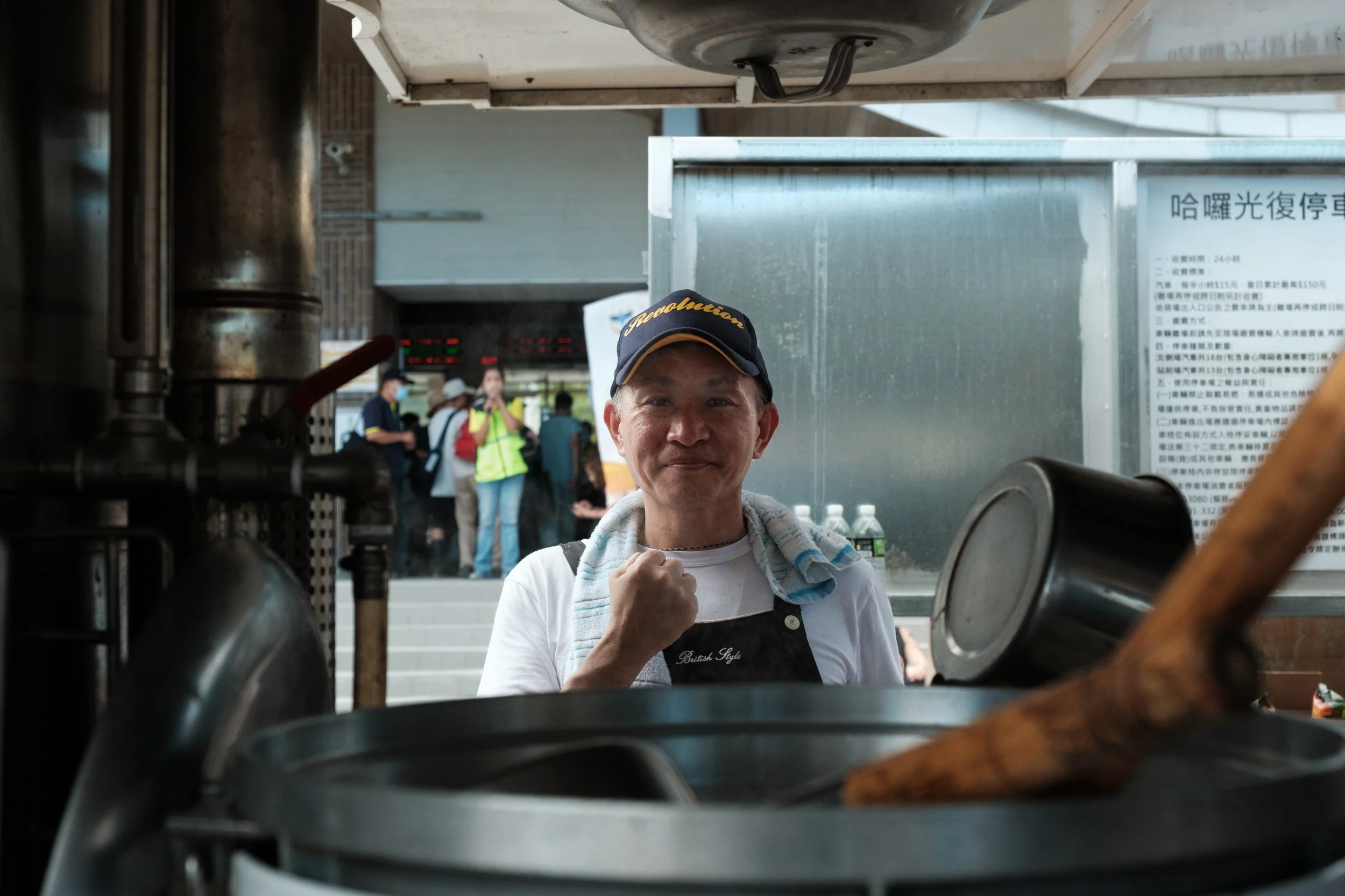 A Guangfu recovery volunteer is standing next to a mobile kitchen in the courtyard outside Guangfu Train Station and showing a sign of solidarity with his hand.