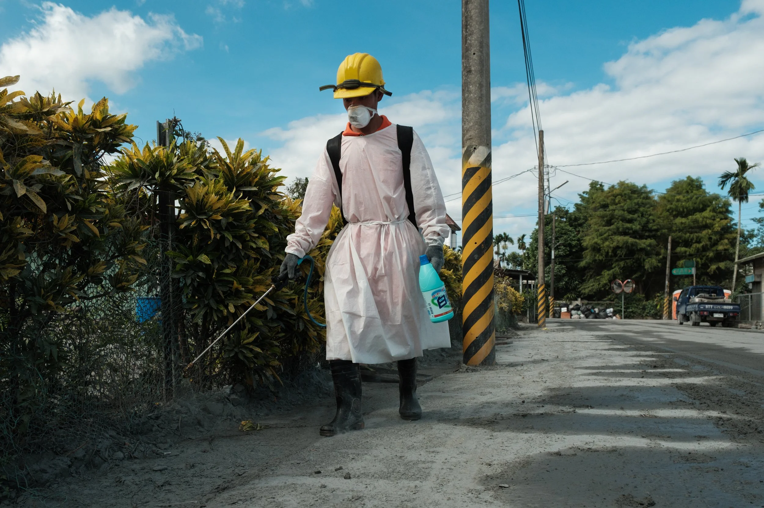 A volunteer in protective clothing is disinfecting a residential street after the 2025 Guangfu flood in Taiwan.