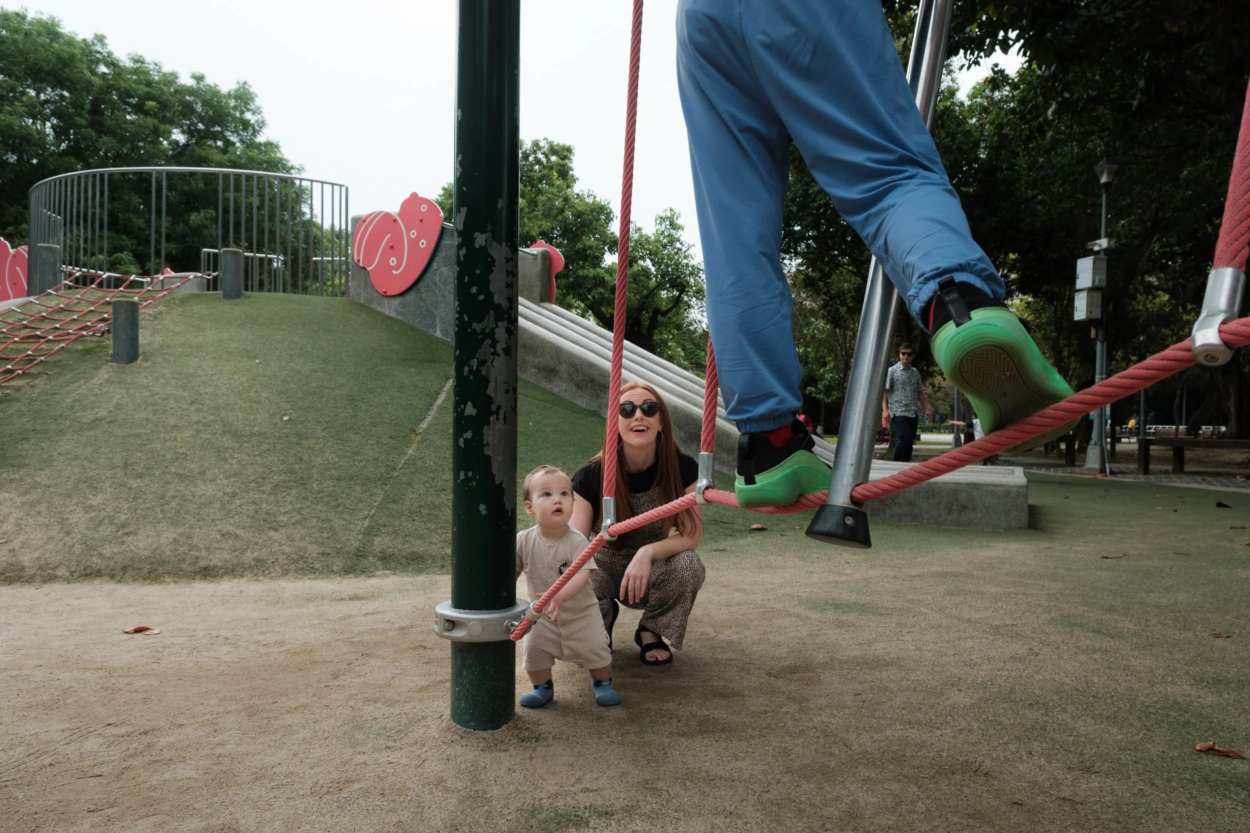 A woman and her toddler son are looking up at an older boy playing on a playground at Rongxing Park in Taipei, Taiwan.
