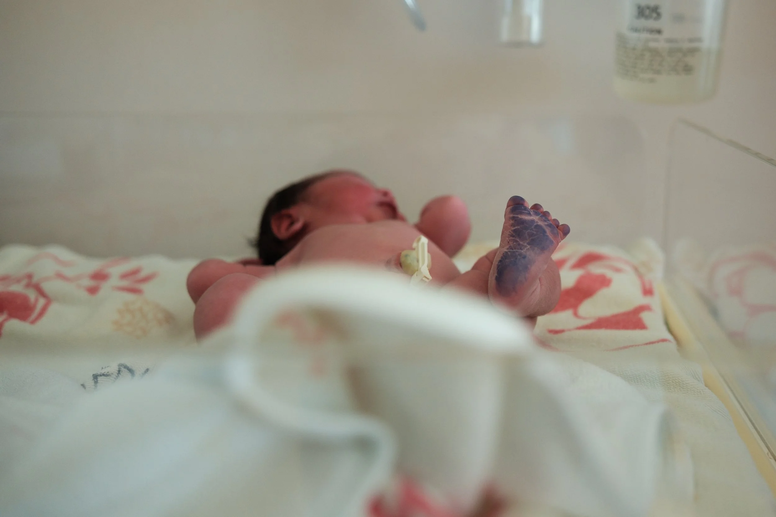Color birth photography image of a newborn's feet in a hospital bassinet at Dianthus shortly after birth.